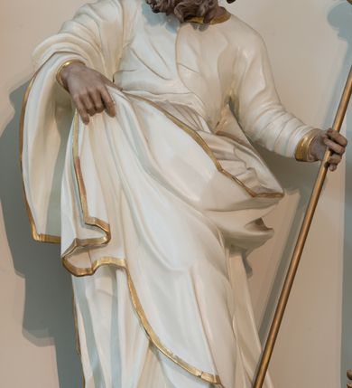 Zdjęcie nr 3: Rzeźba drążona z tyłu, ustawiona na niskiej podstawie. Figura ukazana frontalnie, z lekko uniesioną głową skierowaną w prawo. W lewej, wysuniętej w bok ręce trzyma szuflę pasterską, prawą podtrzymuje z przodu połę płaszcza. Twarz ma pociągła, o starczych rysach, migdałowatych, blisko siebie osadzonych oczach, rozchylonych ustach, okoloną gęstą, długą i kręconą brodą oraz krótkimi włosami rzeźbionymi w pojedyncze pukle. Joachim ubrany jest w długą, białą tunikę ze złoconą lamówką oraz biały płaszcz ze złoconą lamówką zawieszony na prawym ramieniu, otaczający postać, z połą podtrzymywaną z przodu. Ciało polichromowane naturalistycznie. 