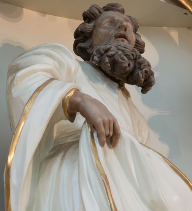 Zdjęcie nr 10: Rzeźba drążona z tyłu, ustawiona na niskiej podstawie. Figura ukazana frontalnie, z lekko uniesioną głową skierowaną w prawo. W lewej, wysuniętej w bok ręce trzyma szuflę pasterską, prawą podtrzymuje z przodu połę płaszcza. Twarz ma pociągła, o starczych rysach, migdałowatych, blisko siebie osadzonych oczach, rozchylonych ustach, okoloną gęstą, długą i kręconą brodą oraz krótkimi włosami rzeźbionymi w pojedyncze pukle. Joachim ubrany jest w długą, białą tunikę ze złoconą lamówką oraz biały płaszcz ze złoconą lamówką zawieszony na prawym ramieniu, otaczający postać, z połą podtrzymywaną z przodu. Ciało polichromowane naturalistycznie. 