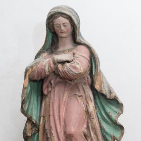 Zdjęcie nr 1: Figura ustawiona na kuli. Maria zwrócona w trzech czwartych w prawo, w kontrapoście, lewą stopą depcze głowę węża, ręce ma skrzyżowane na piersi. Twarz ma owalną, o małych oczach skierowanych w dół, niewielkim nosie i ustach, okoloną długimi włosami, opadającymi na ramiona. Ubrana jest w różową suknię o złoconych lamówkach, obficie fałdowaną, przewiązaną w talii. Na głowę i ramiona ma narzucony zielony płaszcz ze złoconą lamówką, opadający wzdłuż boków i zawieszony na prawym przedramieniu. Polichromia ciała naturalistyczna. 