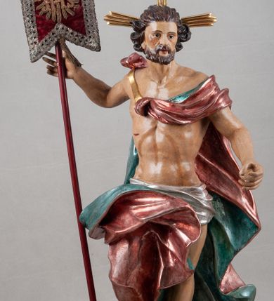 Zdjęcie nr 4: Rzeźba pełna, ustawiona na profilowanym cokole i na rzeźbionej skale. Chrystus zwrócony jest frontalnie, z głową skierowaną w lewą stronę, stoi w silnym kontrapoście. W prawej, uniesionej ręce trzyma drzewce zakończone krzyżem z chorągwią z tkaniny lamowanej koronką, z haftowanym monogramem IHS w glorii, lewą zaś wyciąga w bok. Twarz ma szczupłą, o głęboko osadzonych migdałowatych oczach, niewielkim nosie i małych, pełnych ustach, okoloną brodą oraz krótkimi włosami zaczesanymi do tyłu, układającymi się po bokach w silnie skręcone pukle. Z jego głowy wychodzą trzy wiązki promieni. Chrystus ma przepasane biodra posrebrzonym perizonium. Na prawym ramieniu, na pasku ma zawieszony silnie drapowany i ekspresyjne rozwiany bladoczerwony płaszcz z błękitną podszewką, zarzucony na plecy i na ugiętą prawą nogę. Jego ciało jest szczupłe, o delikatnie zarysowanej, miękko modelowanej muskulaturze torsu i ramion, z zaznaczonymi śladami męki. Na odwrocie podstawy inskrypcja „A(NNO) D(OMINI) / 1781 / A(ntoni) Kornec/ki”. 