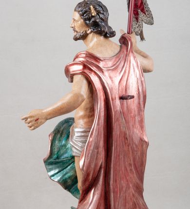 Zdjęcie nr 7: Rzeźba pełna, ustawiona na profilowanym cokole i na rzeźbionej skale. Chrystus zwrócony jest frontalnie, z głową skierowaną w lewą stronę, stoi w silnym kontrapoście. W prawej, uniesionej ręce trzyma drzewce zakończone krzyżem z chorągwią z tkaniny lamowanej koronką, z haftowanym monogramem IHS w glorii, lewą zaś wyciąga w bok. Twarz ma szczupłą, o głęboko osadzonych migdałowatych oczach, niewielkim nosie i małych, pełnych ustach, okoloną brodą oraz krótkimi włosami zaczesanymi do tyłu, układającymi się po bokach w silnie skręcone pukle. Z jego głowy wychodzą trzy wiązki promieni. Chrystus ma przepasane biodra posrebrzonym perizonium. Na prawym ramieniu, na pasku ma zawieszony silnie drapowany i ekspresyjne rozwiany bladoczerwony płaszcz z błękitną podszewką, zarzucony na plecy i na ugiętą prawą nogę. Jego ciało jest szczupłe, o delikatnie zarysowanej, miękko modelowanej muskulaturze torsu i ramion, z zaznaczonymi śladami męki. Na odwrocie podstawy inskrypcja „A(NNO) D(OMINI) / 1781 / A(ntoni) Kornec/ki”. 