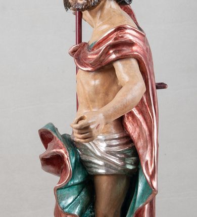 Zdjęcie nr 6: Rzeźba pełna, ustawiona na profilowanym cokole i na rzeźbionej skale. Chrystus zwrócony jest frontalnie, z głową skierowaną w lewą stronę, stoi w silnym kontrapoście. W prawej, uniesionej ręce trzyma drzewce zakończone krzyżem z chorągwią z tkaniny lamowanej koronką, z haftowanym monogramem IHS w glorii, lewą zaś wyciąga w bok. Twarz ma szczupłą, o głęboko osadzonych migdałowatych oczach, niewielkim nosie i małych, pełnych ustach, okoloną brodą oraz krótkimi włosami zaczesanymi do tyłu, układającymi się po bokach w silnie skręcone pukle. Z jego głowy wychodzą trzy wiązki promieni. Chrystus ma przepasane biodra posrebrzonym perizonium. Na prawym ramieniu, na pasku ma zawieszony silnie drapowany i ekspresyjne rozwiany bladoczerwony płaszcz z błękitną podszewką, zarzucony na plecy i na ugiętą prawą nogę. Jego ciało jest szczupłe, o delikatnie zarysowanej, miękko modelowanej muskulaturze torsu i ramion, z zaznaczonymi śladami męki. Na odwrocie podstawy inskrypcja „A(NNO) D(OMINI) / 1781 / A(ntoni) Kornec/ki”. 