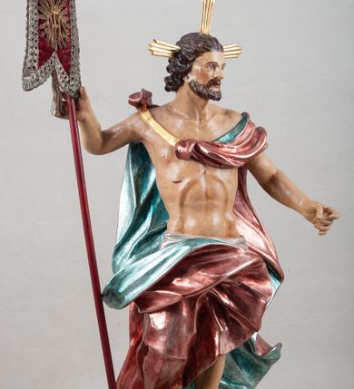 Zdjęcie nr 5: Rzeźba pełna, ustawiona na profilowanym cokole i na rzeźbionej skale. Chrystus zwrócony jest frontalnie, z głową skierowaną w lewą stronę, stoi w silnym kontrapoście. W prawej, uniesionej ręce trzyma drzewce zakończone krzyżem z chorągwią z tkaniny lamowanej koronką, z haftowanym monogramem IHS w glorii, lewą zaś wyciąga w bok. Twarz ma szczupłą, o głęboko osadzonych migdałowatych oczach, niewielkim nosie i małych, pełnych ustach, okoloną brodą oraz krótkimi włosami zaczesanymi do tyłu, układającymi się po bokach w silnie skręcone pukle. Z jego głowy wychodzą trzy wiązki promieni. Chrystus ma przepasane biodra posrebrzonym perizonium. Na prawym ramieniu, na pasku ma zawieszony silnie drapowany i ekspresyjne rozwiany bladoczerwony płaszcz z błękitną podszewką, zarzucony na plecy i na ugiętą prawą nogę. Jego ciało jest szczupłe, o delikatnie zarysowanej, miękko modelowanej muskulaturze torsu i ramion, z zaznaczonymi śladami męki. Na odwrocie podstawy inskrypcja „A(NNO) D(OMINI) / 1781 / A(ntoni) Kornec/ki”. 