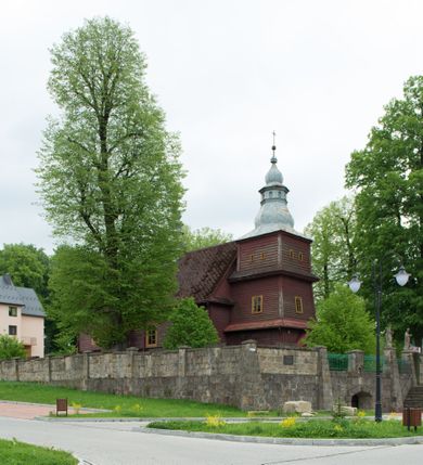 Zdjęcie nr 2: Kościół drewniany o konstrukcji zrębowej, na betonowym podmurowaniu przesłoniętym daszkiem, wieża o konstrukcji słupowej. Elewacje jednolite, szalowane w dolnej połowie pionowo, w górnej połowie poziomo, wzmocnione lisicami. Więźba dachowa drewniana, krokwiowa. Kościół orientowany, jednonawowy, nawa na rzucie prostokąta, prezbiterium nieco węższe, zakończone trójbocznie. Do wschodniej ściany prezbiterium przylega Ogrójec na rzucie prostokąta, od północy piętrowa zakrystia na planie prostokąta z niewielką prostokątną przybudówką od północy. Do zachodniej ściany nawy przylega wieża na planie kwadratu, do południowej ściany nawy kaplica na takim samym planie. 
Pomiędzy nawą a prezbiterium prostokątny otwór tęczowy. Wewnątrz ściany wzmocnione parami lizen, zakończone opasującym całość wnętrza profilowanym gzymsem. Parapet chóru muzycznego w zachodniej części nawy, o wypukłej środkowej części, podparty na czterech filarach. Zakrystia dwupiętrowa ze strychem, na drugim piętrze dawna loża kolatorska otwarta do wnętrza prezbiterium arkadą. Kaplica boczna dwupiętrowa, górne pomieszczenie dzielą od wnętrza dwa okna. Otwory drzwiowe o prostokątnym wykroju, zamknięte drzwiami spągowymi w południowej ścianie nawy oraz prezbiterium, drzwi w zachodniej ścianie dwuskrzydłowe. Wnętrze nakryte pułapami deskowymi o zaokrąglonych fasetach. Posadzka z płyt ceramicznych. 
Elewacja frontowa z dostawioną trójkondygnacyjną, zwężającą się ku górze wieżą, każda kondygnacja oddzielona daszkiem. Na osi oraz na południowej ścianie wejścia do kruchty w przyziemiu wieży z dwuskrzydłowymi drzwiami, frontowe nakryte dwuspadowym daszkiem z niszą na figurę Najświętszego Serca Jezusa. Prostokątne okna z dwóch stron pierwszej kondygnacji, trzech stron drugiej kondygnacji, w partii trzeciej z każdej strony para otworów dzwonnych. W elewacji północnej pięć otworów okiennych w formie stojącego prostokąta, dwa w nawie, po jednym w każdej kondygnacji zakrystii oraz w północnej przybudówce zakrystii wejście i małe prostokątne okienko. W elewacji południowej cztery okna w formie stojącego prostokąta, dwa w nawie i dwa w prezbiterium. W kaplicy bocznej okno i wejście w pierwszej kondygnacji oraz cztery okna w drugiej kondygnacji – dwa na ścianie frontowej oraz po jednym na bocznych. Na ścianie wschodniej prezbiterium Ogrójec w formie głębokiej szalowanej wnęki przesłoniętej dwuspadowym daszkiem. Kościół nakryty dachami dwuspadowymi z ceramicznej dachówki, wyższym nad nawą, niższym nad prezbiterium, nad zakrystią dach dwuspadowy, nad przybudówką pulpitowy. Kaplica przekryta blaszanym dachem dwuspadowym. Wieża zwieńczona hełmem baniastym pokrytym blachą, z ośmioboczną latarnią z otworami dzwonnymi, z pozorną izbicą. W połowie długości dachu nad nawą od strony prezbiterium wznosi się ponad kalenicą wieżyczka na sygnaturkę, na ośmiobocznym obitym blachą trzonie, z latarnią zwieńczoną niewielkim cebulastym, blaszanym hełmem zakończonym kulą z krzyżem. 