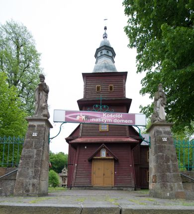 Zdjęcie nr 7: Kościół drewniany o konstrukcji zrębowej, na betonowym podmurowaniu przesłoniętym daszkiem, wieża o konstrukcji słupowej. Elewacje jednolite, szalowane w dolnej połowie pionowo, w górnej połowie poziomo, wzmocnione lisicami. Więźba dachowa drewniana, krokwiowa. Kościół orientowany, jednonawowy, nawa na rzucie prostokąta, prezbiterium nieco węższe, zakończone trójbocznie. Do wschodniej ściany prezbiterium przylega Ogrójec na rzucie prostokąta, od północy piętrowa zakrystia na planie prostokąta z niewielką prostokątną przybudówką od północy. Do zachodniej ściany nawy przylega wieża na planie kwadratu, do południowej ściany nawy kaplica na takim samym planie. 
Pomiędzy nawą a prezbiterium prostokątny otwór tęczowy. Wewnątrz ściany wzmocnione parami lizen, zakończone opasującym całość wnętrza profilowanym gzymsem. Parapet chóru muzycznego w zachodniej części nawy, o wypukłej środkowej części, podparty na czterech filarach. Zakrystia dwupiętrowa ze strychem, na drugim piętrze dawna loża kolatorska otwarta do wnętrza prezbiterium arkadą. Kaplica boczna dwupiętrowa, górne pomieszczenie dzielą od wnętrza dwa okna. Otwory drzwiowe o prostokątnym wykroju, zamknięte drzwiami spągowymi w południowej ścianie nawy oraz prezbiterium, drzwi w zachodniej ścianie dwuskrzydłowe. Wnętrze nakryte pułapami deskowymi o zaokrąglonych fasetach. Posadzka z płyt ceramicznych. 
Elewacja frontowa z dostawioną trójkondygnacyjną, zwężającą się ku górze wieżą, każda kondygnacja oddzielona daszkiem. Na osi oraz na południowej ścianie wejścia do kruchty w przyziemiu wieży z dwuskrzydłowymi drzwiami, frontowe nakryte dwuspadowym daszkiem z niszą na figurę Najświętszego Serca Jezusa. Prostokątne okna z dwóch stron pierwszej kondygnacji, trzech stron drugiej kondygnacji, w partii trzeciej z każdej strony para otworów dzwonnych. W elewacji północnej pięć otworów okiennych w formie stojącego prostokąta, dwa w nawie, po jednym w każdej kondygnacji zakrystii oraz w północnej przybudówce zakrystii wejście i małe prostokątne okienko. W elewacji południowej cztery okna w formie stojącego prostokąta, dwa w nawie i dwa w prezbiterium. W kaplicy bocznej okno i wejście w pierwszej kondygnacji oraz cztery okna w drugiej kondygnacji – dwa na ścianie frontowej oraz po jednym na bocznych. Na ścianie wschodniej prezbiterium Ogrójec w formie głębokiej szalowanej wnęki przesłoniętej dwuspadowym daszkiem. Kościół nakryty dachami dwuspadowymi z ceramicznej dachówki, wyższym nad nawą, niższym nad prezbiterium, nad zakrystią dach dwuspadowy, nad przybudówką pulpitowy. Kaplica przekryta blaszanym dachem dwuspadowym. Wieża zwieńczona hełmem baniastym pokrytym blachą, z ośmioboczną latarnią z otworami dzwonnymi, z pozorną izbicą. W połowie długości dachu nad nawą od strony prezbiterium wznosi się ponad kalenicą wieżyczka na sygnaturkę, na ośmiobocznym obitym blachą trzonie, z latarnią zwieńczoną niewielkim cebulastym, blaszanym hełmem zakończonym kulą z krzyżem. 