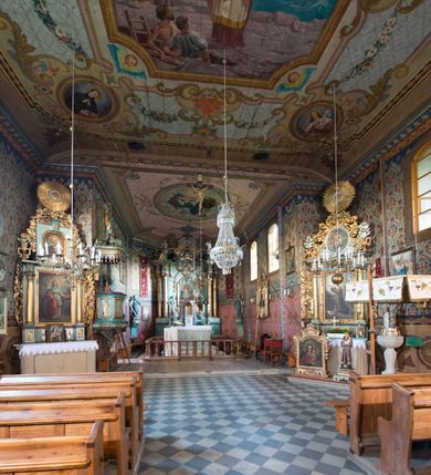 Zdjęcie nr 17: Kościół drewniany o konstrukcji zrębowej, na betonowym podmurowaniu przesłoniętym daszkiem, wieża o konstrukcji słupowej. Elewacje jednolite, szalowane w dolnej połowie pionowo, w górnej połowie poziomo, wzmocnione lisicami. Więźba dachowa drewniana, krokwiowa. Kościół orientowany, jednonawowy, nawa na rzucie prostokąta, prezbiterium nieco węższe, zakończone trójbocznie. Do wschodniej ściany prezbiterium przylega Ogrójec na rzucie prostokąta, od północy piętrowa zakrystia na planie prostokąta z niewielką prostokątną przybudówką od północy. Do zachodniej ściany nawy przylega wieża na planie kwadratu, do południowej ściany nawy kaplica na takim samym planie. 
Pomiędzy nawą a prezbiterium prostokątny otwór tęczowy. Wewnątrz ściany wzmocnione parami lizen, zakończone opasującym całość wnętrza profilowanym gzymsem. Parapet chóru muzycznego w zachodniej części nawy, o wypukłej środkowej części, podparty na czterech filarach. Zakrystia dwupiętrowa ze strychem, na drugim piętrze dawna loża kolatorska otwarta do wnętrza prezbiterium arkadą. Kaplica boczna dwupiętrowa, górne pomieszczenie dzielą od wnętrza dwa okna. Otwory drzwiowe o prostokątnym wykroju, zamknięte drzwiami spągowymi w południowej ścianie nawy oraz prezbiterium, drzwi w zachodniej ścianie dwuskrzydłowe. Wnętrze nakryte pułapami deskowymi o zaokrąglonych fasetach. Posadzka z płyt ceramicznych. 
Elewacja frontowa z dostawioną trójkondygnacyjną, zwężającą się ku górze wieżą, każda kondygnacja oddzielona daszkiem. Na osi oraz na południowej ścianie wejścia do kruchty w przyziemiu wieży z dwuskrzydłowymi drzwiami, frontowe nakryte dwuspadowym daszkiem z niszą na figurę Najświętszego Serca Jezusa. Prostokątne okna z dwóch stron pierwszej kondygnacji, trzech stron drugiej kondygnacji, w partii trzeciej z każdej strony para otworów dzwonnych. W elewacji północnej pięć otworów okiennych w formie stojącego prostokąta, dwa w nawie, po jednym w każdej kondygnacji zakrystii oraz w północnej przybudówce zakrystii wejście i małe prostokątne okienko. W elewacji południowej cztery okna w formie stojącego prostokąta, dwa w nawie i dwa w prezbiterium. W kaplicy bocznej okno i wejście w pierwszej kondygnacji oraz cztery okna w drugiej kondygnacji – dwa na ścianie frontowej oraz po jednym na bocznych. Na ścianie wschodniej prezbiterium Ogrójec w formie głębokiej szalowanej wnęki przesłoniętej dwuspadowym daszkiem. Kościół nakryty dachami dwuspadowymi z ceramicznej dachówki, wyższym nad nawą, niższym nad prezbiterium, nad zakrystią dach dwuspadowy, nad przybudówką pulpitowy. Kaplica przekryta blaszanym dachem dwuspadowym. Wieża zwieńczona hełmem baniastym pokrytym blachą, z ośmioboczną latarnią z otworami dzwonnymi, z pozorną izbicą. W połowie długości dachu nad nawą od strony prezbiterium wznosi się ponad kalenicą wieżyczka na sygnaturkę, na ośmiobocznym obitym blachą trzonie, z latarnią zwieńczoną niewielkim cebulastym, blaszanym hełmem zakończonym kulą z krzyżem. 