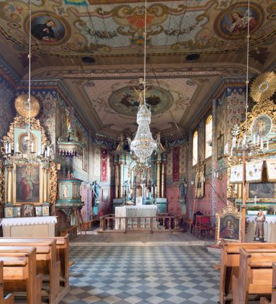 Zdjęcie nr 18: Kościół drewniany o konstrukcji zrębowej, na betonowym podmurowaniu przesłoniętym daszkiem, wieża o konstrukcji słupowej. Elewacje jednolite, szalowane w dolnej połowie pionowo, w górnej połowie poziomo, wzmocnione lisicami. Więźba dachowa drewniana, krokwiowa. Kościół orientowany, jednonawowy, nawa na rzucie prostokąta, prezbiterium nieco węższe, zakończone trójbocznie. Do wschodniej ściany prezbiterium przylega Ogrójec na rzucie prostokąta, od północy piętrowa zakrystia na planie prostokąta z niewielką prostokątną przybudówką od północy. Do zachodniej ściany nawy przylega wieża na planie kwadratu, do południowej ściany nawy kaplica na takim samym planie. 
Pomiędzy nawą a prezbiterium prostokątny otwór tęczowy. Wewnątrz ściany wzmocnione parami lizen, zakończone opasującym całość wnętrza profilowanym gzymsem. Parapet chóru muzycznego w zachodniej części nawy, o wypukłej środkowej części, podparty na czterech filarach. Zakrystia dwupiętrowa ze strychem, na drugim piętrze dawna loża kolatorska otwarta do wnętrza prezbiterium arkadą. Kaplica boczna dwupiętrowa, górne pomieszczenie dzielą od wnętrza dwa okna. Otwory drzwiowe o prostokątnym wykroju, zamknięte drzwiami spągowymi w południowej ścianie nawy oraz prezbiterium, drzwi w zachodniej ścianie dwuskrzydłowe. Wnętrze nakryte pułapami deskowymi o zaokrąglonych fasetach. Posadzka z płyt ceramicznych. 
Elewacja frontowa z dostawioną trójkondygnacyjną, zwężającą się ku górze wieżą, każda kondygnacja oddzielona daszkiem. Na osi oraz na południowej ścianie wejścia do kruchty w przyziemiu wieży z dwuskrzydłowymi drzwiami, frontowe nakryte dwuspadowym daszkiem z niszą na figurę Najświętszego Serca Jezusa. Prostokątne okna z dwóch stron pierwszej kondygnacji, trzech stron drugiej kondygnacji, w partii trzeciej z każdej strony para otworów dzwonnych. W elewacji północnej pięć otworów okiennych w formie stojącego prostokąta, dwa w nawie, po jednym w każdej kondygnacji zakrystii oraz w północnej przybudówce zakrystii wejście i małe prostokątne okienko. W elewacji południowej cztery okna w formie stojącego prostokąta, dwa w nawie i dwa w prezbiterium. W kaplicy bocznej okno i wejście w pierwszej kondygnacji oraz cztery okna w drugiej kondygnacji – dwa na ścianie frontowej oraz po jednym na bocznych. Na ścianie wschodniej prezbiterium Ogrójec w formie głębokiej szalowanej wnęki przesłoniętej dwuspadowym daszkiem. Kościół nakryty dachami dwuspadowymi z ceramicznej dachówki, wyższym nad nawą, niższym nad prezbiterium, nad zakrystią dach dwuspadowy, nad przybudówką pulpitowy. Kaplica przekryta blaszanym dachem dwuspadowym. Wieża zwieńczona hełmem baniastym pokrytym blachą, z ośmioboczną latarnią z otworami dzwonnymi, z pozorną izbicą. W połowie długości dachu nad nawą od strony prezbiterium wznosi się ponad kalenicą wieżyczka na sygnaturkę, na ośmiobocznym obitym blachą trzonie, z latarnią zwieńczoną niewielkim cebulastym, blaszanym hełmem zakończonym kulą z krzyżem. 