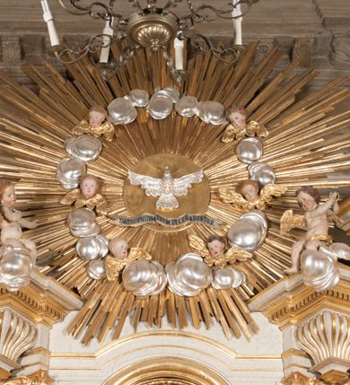 Zdjęcie nr 5: Ołtarz architektoniczny, przyścienny, jednoosiowy, jednokondygnacyjny z mensą. Mensa prosta, kamienna; antepedium płaskorzeźbione ze sceną Zesłania Ducha Świętego. Kompozycja jest niemal symetryczna, postacie apostołów oraz dwie Marie siedzą lub stoją poniżej rozchodzących się promieni glorii. Nastawa ołtarzowa ustawiona na wysokim, zdwojonym cokole, którego szersza oś środkowa jest flankowana parami cokołów ustawionych skośnie. Pierwsza kondygnacja również ustawiona na cokole, którego pola wypełniają płyciny z płaskorzeźbioną, symetryczną dekoracją z ceownicami wokół kwiatu róży. Na środku, na mensie prostopadłościenne tabernakulum na cokole. Na jego ścianie frontowej wypełnione czerwonym kolorem drzwi w kształcie stojącego prostokąta zamkniętego od góry łukiem nadwieszonym, flankowane kolumienkami jońskimi. 
W polu środkowym pierwszej kondygnacji ołtarza obraz „Oblicze Chrystusa” (XVII w.) w profilowanej, prostokątnej ramie z uskokiem i półkolistym zamknięciem od góry. Pole flankowane skośnie ustawionymi kolumnami korynckimi na tle pilastrów, wspierającymi wyłamane nad nimi belkowanie i fragmenty przerwanego przyczółka. Trzony kolumn ozdobione plastycznymi płomieniami. Na pilastrach płyciny z wypełnieniem z płaskorzeźbionych ornamentów o motywach regencyjnych. Na tle pilastrów, po obu stronach środkowego obrazu, rzeźbione figury św. Heleny i św. Barbary w obficie drapowanych szatach. 
Zwieńczenie ołtarza w formie glorii promienistej z gołębicą Ducha Świętego pośrodku. Poniżej niej, na banderoli inskrypcja „EMITTE  SPIRITUM TUUM ET CREABUNTUR”. Przedstawienie ujęte otokiem utworzonym z obłoków i uskrzydlonych główek. Po bokach, na częściach przerwanego belkowania, na obłokach siedzą putta. Są zwrócone do siebie i spoglądają lekko w dół. Mają uniesione ręce i są przepasane złotymi szarfami. 
Struktura ołtarza dekorowana imitacją marmoryzacji za pomocą polichromii na kolor jasnoszary z ciemniejszymi żyłkami; profile, ornamenty, gloria, szaty świętych złocone; obłoki, gołębica, elementy strojów, fragmenty antepedium srebrzone; polichromia w partiach ciała postaci naturalistyczna. 