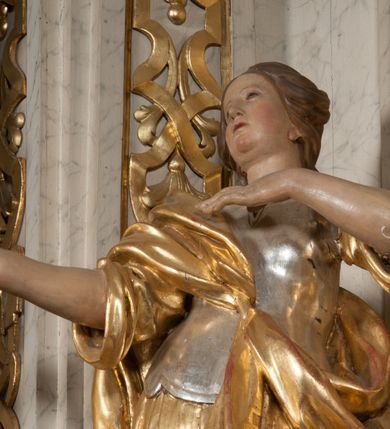 Zdjęcie nr 20: Ołtarz architektoniczny, przyścienny, jednoosiowy, jednokondygnacyjny z mensą. Mensa prosta, kamienna; antepedium płaskorzeźbione ze sceną Zesłania Ducha Świętego. Kompozycja jest niemal symetryczna, postacie apostołów oraz dwie Marie siedzą lub stoją poniżej rozchodzących się promieni glorii. Nastawa ołtarzowa ustawiona na wysokim, zdwojonym cokole, którego szersza oś środkowa jest flankowana parami cokołów ustawionych skośnie. Pierwsza kondygnacja również ustawiona na cokole, którego pola wypełniają płyciny z płaskorzeźbioną, symetryczną dekoracją z ceownicami wokół kwiatu róży. Na środku, na mensie prostopadłościenne tabernakulum na cokole. Na jego ścianie frontowej wypełnione czerwonym kolorem drzwi w kształcie stojącego prostokąta zamkniętego od góry łukiem nadwieszonym, flankowane kolumienkami jońskimi. 
W polu środkowym pierwszej kondygnacji ołtarza obraz „Oblicze Chrystusa” (XVII w.) w profilowanej, prostokątnej ramie z uskokiem i półkolistym zamknięciem od góry. Pole flankowane skośnie ustawionymi kolumnami korynckimi na tle pilastrów, wspierającymi wyłamane nad nimi belkowanie i fragmenty przerwanego przyczółka. Trzony kolumn ozdobione plastycznymi płomieniami. Na pilastrach płyciny z wypełnieniem z płaskorzeźbionych ornamentów o motywach regencyjnych. Na tle pilastrów, po obu stronach środkowego obrazu, rzeźbione figury św. Heleny i św. Barbary w obficie drapowanych szatach. 
Zwieńczenie ołtarza w formie glorii promienistej z gołębicą Ducha Świętego pośrodku. Poniżej niej, na banderoli inskrypcja „EMITTE  SPIRITUM TUUM ET CREABUNTUR”. Przedstawienie ujęte otokiem utworzonym z obłoków i uskrzydlonych główek. Po bokach, na częściach przerwanego belkowania, na obłokach siedzą putta. Są zwrócone do siebie i spoglądają lekko w dół. Mają uniesione ręce i są przepasane złotymi szarfami. 
Struktura ołtarza dekorowana imitacją marmoryzacji za pomocą polichromii na kolor jasnoszary z ciemniejszymi żyłkami; profile, ornamenty, gloria, szaty świętych złocone; obłoki, gołębica, elementy strojów, fragmenty antepedium srebrzone; polichromia w partiach ciała postaci naturalistyczna. 