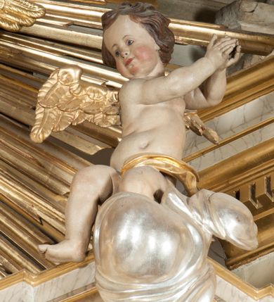 Zdjęcie nr 23: Ołtarz architektoniczny, przyścienny, jednoosiowy, jednokondygnacyjny z mensą. Mensa prosta, kamienna; antepedium płaskorzeźbione ze sceną Zesłania Ducha Świętego. Kompozycja jest niemal symetryczna, postacie apostołów oraz dwie Marie siedzą lub stoją poniżej rozchodzących się promieni glorii. Nastawa ołtarzowa ustawiona na wysokim, zdwojonym cokole, którego szersza oś środkowa jest flankowana parami cokołów ustawionych skośnie. Pierwsza kondygnacja również ustawiona na cokole, którego pola wypełniają płyciny z płaskorzeźbioną, symetryczną dekoracją z ceownicami wokół kwiatu róży. Na środku, na mensie prostopadłościenne tabernakulum na cokole. Na jego ścianie frontowej wypełnione czerwonym kolorem drzwi w kształcie stojącego prostokąta zamkniętego od góry łukiem nadwieszonym, flankowane kolumienkami jońskimi. 
W polu środkowym pierwszej kondygnacji ołtarza obraz „Oblicze Chrystusa” (XVII w.) w profilowanej, prostokątnej ramie z uskokiem i półkolistym zamknięciem od góry. Pole flankowane skośnie ustawionymi kolumnami korynckimi na tle pilastrów, wspierającymi wyłamane nad nimi belkowanie i fragmenty przerwanego przyczółka. Trzony kolumn ozdobione plastycznymi płomieniami. Na pilastrach płyciny z wypełnieniem z płaskorzeźbionych ornamentów o motywach regencyjnych. Na tle pilastrów, po obu stronach środkowego obrazu, rzeźbione figury św. Heleny i św. Barbary w obficie drapowanych szatach. 
Zwieńczenie ołtarza w formie glorii promienistej z gołębicą Ducha Świętego pośrodku. Poniżej niej, na banderoli inskrypcja „EMITTE  SPIRITUM TUUM ET CREABUNTUR”. Przedstawienie ujęte otokiem utworzonym z obłoków i uskrzydlonych główek. Po bokach, na częściach przerwanego belkowania, na obłokach siedzą putta. Są zwrócone do siebie i spoglądają lekko w dół. Mają uniesione ręce i są przepasane złotymi szarfami. 
Struktura ołtarza dekorowana imitacją marmoryzacji za pomocą polichromii na kolor jasnoszary z ciemniejszymi żyłkami; profile, ornamenty, gloria, szaty świętych złocone; obłoki, gołębica, elementy strojów, fragmenty antepedium srebrzone; polichromia w partiach ciała postaci naturalistyczna. 