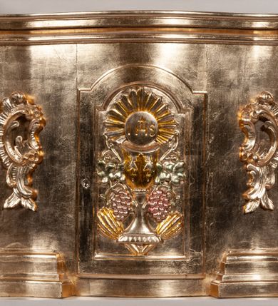 Zdjęcie nr 10: Ołtarz architektoniczny, przyścienny, jednokondygnacyjny, jednoosiowy, w formie podwójnej aediculi. Mensa prostopadłościenna, z płyciną w kształcie leżącego prostokąta wypełnionego marmoryzacją i obwiedzionego profilowaną ramą. Na mensie tabernakulum na planie zbliżonym do owalu, o wklęsło-wypukłej linii ścian. Części boczne na cokole, w środkowej drzwiczki w kształcie stojącego prostokąta zamkniętego łukiem nadwieszonym z symetryczną dekoracją składającą się z kielicha z hostią otoczoną glorią promienistą na tle kłosów zbóż oraz kiści winogron. Na bocznych ściankach dekoracja z ornamentu rocaille&#039;owego. Tabernakulum od góry zamknięte profilowanym gzymsem. 
Nastawa na wysokim, trójdzielnym cokole dekorowanym prostokątnymi płycinami. W polu głównym rama w kształcie stojącego prostokąta zamkniętego od góry łukiem wklęsło-wypukłym z uskokiem. W niej obraz z przedstawieniem Ecce Homo w owalnej ramie poniżej kokardy uwitej ze złotej wstęgi, i powyżej tabliczki z napisem „O MÓJ JEZU MIŁOSIERDZIA!”. Pole flankowane zakończonymi głowicami jońskimi pilastrami podtrzymującymi proste belkowanie. Przed nimi figury dwóch ewangelistów. Całość ujęta dwiema żłobkowanymi kolumnami o kapitelach kompozytowych, wspierającymi pełne belkowanie zwieńczone trójkątnym przyczółkiem z zatkniętym na szczycie krzyżem łacińskim. Na osi kolumn, na belkowaniu wazony z kwiatami. 
Wokół ramy, na trzonach pilastrów, między belkowaniami oraz na fryzie podtrzymywanym przez kolumny dekoracja z elementów roślinnych w postaci pęków kwiatów z liśćmi lub wici; na środku fryzu dwa skrzyżowane młoty; w polu przyczółka uskrzydlona główka anielska. 
Struktura w kolorze kremowym lub marmoryzowana na kolor różowy; kolumny, profile, ornamenty i dekoracje złocone; skrzyżowane młoty, elementy kwiatów i krzyża srebrzone. 