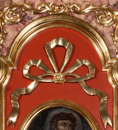 Zdjęcie nr 7: Ołtarz architektoniczny, przyścienny, jednokondygnacyjny, jednoosiowy, w formie podwójnej aediculi. Mensa prostopadłościenna, z płyciną w kształcie leżącego prostokąta wypełnionego marmoryzacją i obwiedzionego profilowaną ramą. Na mensie tabernakulum na planie zbliżonym do owalu, o wklęsło-wypukłej linii ścian. Części boczne na cokole, w środkowej drzwiczki w kształcie stojącego prostokąta zamkniętego łukiem nadwieszonym z symetryczną dekoracją składającą się z kielicha z hostią otoczoną glorią promienistą na tle kłosów zbóż oraz kiści winogron. Na bocznych ściankach dekoracja z ornamentu rocaille&#039;owego. Tabernakulum od góry zamknięte profilowanym gzymsem. 
Nastawa na wysokim, trójdzielnym cokole dekorowanym prostokątnymi płycinami. W polu głównym rama w kształcie stojącego prostokąta zamkniętego od góry łukiem wklęsło-wypukłym z uskokiem. W niej obraz z przedstawieniem Ecce Homo w owalnej ramie poniżej kokardy uwitej ze złotej wstęgi, i powyżej tabliczki z napisem „O MÓJ JEZU MIŁOSIERDZIA!”. Pole flankowane zakończonymi głowicami jońskimi pilastrami podtrzymującymi proste belkowanie. Przed nimi figury dwóch ewangelistów. Całość ujęta dwiema żłobkowanymi kolumnami o kapitelach kompozytowych, wspierającymi pełne belkowanie zwieńczone trójkątnym przyczółkiem z zatkniętym na szczycie krzyżem łacińskim. Na osi kolumn, na belkowaniu wazony z kwiatami. 
Wokół ramy, na trzonach pilastrów, między belkowaniami oraz na fryzie podtrzymywanym przez kolumny dekoracja z elementów roślinnych w postaci pęków kwiatów z liśćmi lub wici; na środku fryzu dwa skrzyżowane młoty; w polu przyczółka uskrzydlona główka anielska. 
Struktura w kolorze kremowym lub marmoryzowana na kolor różowy; kolumny, profile, ornamenty i dekoracje złocone; skrzyżowane młoty, elementy kwiatów i krzyża srebrzone. 