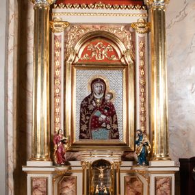 Zdjęcie nr 1: Ołtarz architektoniczny, przyścienny, jednokondygnacyjny, jednoosiowy, w formie aediculi, ustawiony na wysokim cokole. Do niego przystawiona prostopadłościenna mensa, z antepedium ozdobionym trzema płycinami: zewnętrze mają kształt kwadratu i są wypełnione polichromią imitującą marmoryzację, środkowa, w kształcie leżącego prostokąta, ozdobiona jest monogramem maryjnym. Na mensie tabernakulum z tronem do wystawiania, na rzucie zbliżonym do owalu. Ustawione na wysokim cokole, w którym prostokątne drzwiczki. Tron do wystawiania w formie dekorowanej kotarą niszy wypełnionej grupą Ukrzyżowania z Marią i św. Janem, utrzymanej w stylistyce ludowej. Na cokole przedstawiono narzędzia murarskie oraz Serce Jezusa. Niszę flankują pary kolumn, całość wieńczy silnie profilowane belkowanie.  
Nastawa ołtarzowa na własnym cokole z wyodrębnionymi po bokach prostopadłościennymi postumentami pod znajdujące się wyżej kolumny, dekorowanymi od przodu prostokątnymi płycinami; inne powierzchnie partii cokołowej ołtarza (m.in. po bokach tabernakulum) ożywione prostokątnymi, zestawionymi względem siebie w symetryczne pary płycinami, każda ze ściętym jednym z górnych narożników. W polu centralnym środkowej partii retabulum rama w kształcie pionowego prostokąta zamkniętego od góry łukiem wklęsło-wypukłym z uskokiem. W niej obraz z przedstawieniem Matki Boskiej w typie Śnieżnej trzymającej szkaplerz, wyobrażonej poniżej monogramu maryjnego uwitego ze złotej wstęgi. Pole flankowane pilastrami jońskimi, przed którymi ustawione kolumny o kapitelach utworzonych z kimationów, podtrzymujące pełne belkowanie przełamujące się na ich osi. Fryz belkowania dekorowany kolistymi medalionami z głowami aniołków i głową Chrystusa na środku. Przy podstawach kolumn dwie figury ewangelistów. Ponad belkowaniem rozsunięte fragmenty przerwanego, trójkątnego przyczółka. Na belkowaniu, w centrum figura św. Józefa z Dzieciątkiem na lewym ramieniu i lilią w prawej ręce. W zwieńczeniu na osi kolumn figurki siedzących aniołków, trzymających narzędzia murarskie. 
Trzony pilastrów dekorowane kampanulami, ich głowice girlandami kwiatów oraz muszlami; w tle pola głównej kondygnacji gałązki kwiatowe; gzyms tamże w formie fryzu palmetowego, kolejny na mensie.  
Struktura w kolorze kremowym lub pokryta imitacją marmoryzacji w kolorze różowym; niektóre pola malowane na kolor ciemnopomarańczowy; kolumny, profile, ornamenty złocone; elementy figur, medalionów oraz głowic złocone i srebrzone.