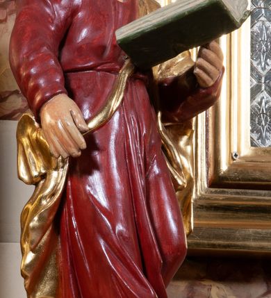 Zdjęcie nr 5: Ołtarz architektoniczny, przyścienny, jednokondygnacyjny, jednoosiowy, w formie aediculi, ustawiony na wysokim cokole. Do niego przystawiona prostopadłościenna mensa, z antepedium ozdobionym trzema płycinami: zewnętrze mają kształt kwadratu i są wypełnione polichromią imitującą marmoryzację, środkowa, w kształcie leżącego prostokąta, ozdobiona jest monogramem maryjnym. Na mensie tabernakulum z tronem do wystawiania, na rzucie zbliżonym do owalu. Ustawione na wysokim cokole, w którym prostokątne drzwiczki. Tron do wystawiania w formie dekorowanej kotarą niszy wypełnionej grupą Ukrzyżowania z Marią i św. Janem, utrzymanej w stylistyce ludowej. Na cokole przedstawiono narzędzia murarskie oraz Serce Jezusa. Niszę flankują pary kolumn, całość wieńczy silnie profilowane belkowanie.  
Nastawa ołtarzowa na własnym cokole z wyodrębnionymi po bokach prostopadłościennymi postumentami pod znajdujące się wyżej kolumny, dekorowanymi od przodu prostokątnymi płycinami; inne powierzchnie partii cokołowej ołtarza (m.in. po bokach tabernakulum) ożywione prostokątnymi, zestawionymi względem siebie w symetryczne pary płycinami, każda ze ściętym jednym z górnych narożników. W polu centralnym środkowej partii retabulum rama w kształcie pionowego prostokąta zamkniętego od góry łukiem wklęsło-wypukłym z uskokiem. W niej obraz z przedstawieniem Matki Boskiej w typie Śnieżnej trzymającej szkaplerz, wyobrażonej poniżej monogramu maryjnego uwitego ze złotej wstęgi. Pole flankowane pilastrami jońskimi, przed którymi ustawione kolumny o kapitelach utworzonych z kimationów, podtrzymujące pełne belkowanie przełamujące się na ich osi. Fryz belkowania dekorowany kolistymi medalionami z głowami aniołków i głową Chrystusa na środku. Przy podstawach kolumn dwie figury ewangelistów. Ponad belkowaniem rozsunięte fragmenty przerwanego, trójkątnego przyczółka. Na belkowaniu, w centrum figura św. Józefa z Dzieciątkiem na lewym ramieniu i lilią w prawej ręce. W zwieńczeniu na osi kolumn figurki siedzących aniołków, trzymających narzędzia murarskie. 
Trzony pilastrów dekorowane kampanulami, ich głowice girlandami kwiatów oraz muszlami; w tle pola głównej kondygnacji gałązki kwiatowe; gzyms tamże w formie fryzu palmetowego, kolejny na mensie.  
Struktura w kolorze kremowym lub pokryta imitacją marmoryzacji w kolorze różowym; niektóre pola malowane na kolor ciemnopomarańczowy; kolumny, profile, ornamenty złocone; elementy figur, medalionów oraz głowic złocone i srebrzone.