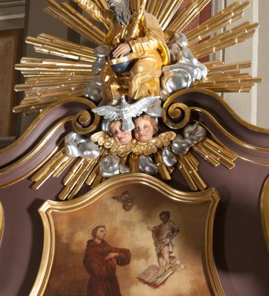 Zdjęcie nr 5: Ołtarz przyścienny, architektoniczny, jednoosiowy, jednokondygnacjowy ze zwieńczeniem. Retabulum ustawione na wysokim cokole, przed którym stoi mensa w typie sarkofagowym. Na mensie tabernakulum w formie prostopadłościanu, którego ściana frontowa jest flankowana parą dostawionych skośnie kolumn, a tylna wolutami. Tabernakulum na cokole, na ścianie frontowej drzwi w kształcie prostokąta zamkniętego od góry łukiem nadwieszonym, z przedstawieniem wypukłorzeźbionej, silnie plastycznej sceny chrztu Chrystusa. Z prawej strony św. Jan Chrzciciel, który prawym kolanem klęczy na głazie, prawą ręką polewa wodą głowę stojącego po lewej stronie Chrystusa. Za nimi dwie postaci, powyżej gołębica Ducha Świętego. W górnych narożnikach ściany frontowej tabernakulum dwa, symetrycznie ułożone ornamenty rocaille. Główne pole właściwego retabulum flankują kolumny korynckie o trzonach dekorowanych wicią, ustawione na tle zwielokrotnionych pilastrów; podpory posadowione na ukośnie ustawionych, rozsuniętych postumentach dekorowanych kwadratowymi płycinami, dźwigają  belkowanie przełamane na ich osiach, z odcinkami także ustawionymi skośnie. W prostokątnym polu głównym nastawy ołtarzowej obraz z przedstawieniem Matki Boskiej Bolesnej poniżej monogramu maryjnego uwitego ze wstęgi, w prostokątnej ramie zamkniętej od góry łukiem nadwieszonym. Górne naroża pola wypełniają płomieniste motywy rocaille przechodzące w dół w fantazyjną wić roślinną.  Na fryzie belkowania umieszczono ornament roślinny z muszlami, a dolna część gzymsu ma formę pasa ażurowej dekoracji z motywów rocaille na czerwonym tle. Na środku tej dekoracji niewielki kartusz z napisem. Na rozsuniętych odcinkach belkowania, na osi kolumn, umieszczone fragmenty pękniętego półkolistego przyczółka; na nich siedzą anioły. Zwieńczenie umieszczone pomiędzy tymi odcinkami w formie ścianki o ogólnym zarysie trapezu o wklęsłych bokach. Wypełnia ją obraz z przedstawieniem św. Antoniego we wklęsło-wypukłej ramie powtarzającej zarys zwieńczenia, które od góry zamknięte jest dwoma wolutami. W miejscu ich styku, na osi, rzeźbione przedstawienie tronującego Boga Ojca pośród chmur, powyżej główek anielskich i na tle glorii promienistej. Bóg prawą rękę wznosi do góry, lewą trzyma na jabłku królewskim i przytrzymuje berło, u stóp gołębica Ducha Świętego. Struktura ołtarza malowana na kolor brązowy; profile, detale, ornamenty i kolumny złocone, postacie w partiach karnacji  polichromowane naturalistycznie.