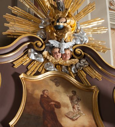 Zdjęcie nr 6: Ołtarz przyścienny, architektoniczny, jednoosiowy, jednokondygnacjowy ze zwieńczeniem. Retabulum ustawione na wysokim cokole, przed którym stoi mensa w typie sarkofagowym. Na mensie tabernakulum w formie prostopadłościanu, którego ściana frontowa jest flankowana parą dostawionych skośnie kolumn, a tylna wolutami. Tabernakulum na cokole, na ścianie frontowej drzwi w kształcie prostokąta zamkniętego od góry łukiem nadwieszonym, z przedstawieniem wypukłorzeźbionej, silnie plastycznej sceny chrztu Chrystusa. Z prawej strony św. Jan Chrzciciel, który prawym kolanem klęczy na głazie, prawą ręką polewa wodą głowę stojącego po lewej stronie Chrystusa. Za nimi dwie postaci, powyżej gołębica Ducha Świętego. W górnych narożnikach ściany frontowej tabernakulum dwa, symetrycznie ułożone ornamenty rocaille. Główne pole właściwego retabulum flankują kolumny korynckie o trzonach dekorowanych wicią, ustawione na tle zwielokrotnionych pilastrów; podpory posadowione na ukośnie ustawionych, rozsuniętych postumentach dekorowanych kwadratowymi płycinami, dźwigają  belkowanie przełamane na ich osiach, z odcinkami także ustawionymi skośnie. W prostokątnym polu głównym nastawy ołtarzowej obraz z przedstawieniem Matki Boskiej Bolesnej poniżej monogramu maryjnego uwitego ze wstęgi, w prostokątnej ramie zamkniętej od góry łukiem nadwieszonym. Górne naroża pola wypełniają płomieniste motywy rocaille przechodzące w dół w fantazyjną wić roślinną.  Na fryzie belkowania umieszczono ornament roślinny z muszlami, a dolna część gzymsu ma formę pasa ażurowej dekoracji z motywów rocaille na czerwonym tle. Na środku tej dekoracji niewielki kartusz z napisem. Na rozsuniętych odcinkach belkowania, na osi kolumn, umieszczone fragmenty pękniętego półkolistego przyczółka; na nich siedzą anioły. Zwieńczenie umieszczone pomiędzy tymi odcinkami w formie ścianki o ogólnym zarysie trapezu o wklęsłych bokach. Wypełnia ją obraz z przedstawieniem św. Antoniego we wklęsło-wypukłej ramie powtarzającej zarys zwieńczenia, które od góry zamknięte jest dwoma wolutami. W miejscu ich styku, na osi, rzeźbione przedstawienie tronującego Boga Ojca pośród chmur, powyżej główek anielskich i na tle glorii promienistej. Bóg prawą rękę wznosi do góry, lewą trzyma na jabłku królewskim i przytrzymuje berło, u stóp gołębica Ducha Świętego. Struktura ołtarza malowana na kolor brązowy; profile, detale, ornamenty i kolumny złocone, postacie w partiach karnacji  polichromowane naturalistycznie.