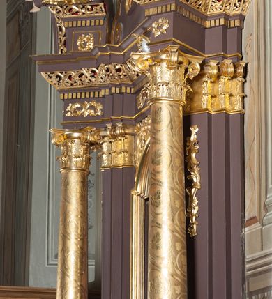 Zdjęcie nr 4: Ołtarz przyścienny, architektoniczny, jednoosiowy, jednokondygnacjowy ze zwieńczeniem. Retabulum ustawione na wysokim cokole, przed którym stoi mensa w typie sarkofagowym. Na mensie tabernakulum w formie prostopadłościanu, którego ściana frontowa jest flankowana parą dostawionych skośnie kolumn, a tylna wolutami. Tabernakulum na cokole, na ścianie frontowej drzwi w kształcie prostokąta zamkniętego od góry łukiem nadwieszonym, z przedstawieniem wypukłorzeźbionej, silnie plastycznej sceny chrztu Chrystusa. Z prawej strony św. Jan Chrzciciel, który prawym kolanem klęczy na głazie, prawą ręką polewa wodą głowę stojącego po lewej stronie Chrystusa. Za nimi dwie postaci, powyżej gołębica Ducha Świętego. W górnych narożnikach ściany frontowej tabernakulum dwa, symetrycznie ułożone ornamenty rocaille. Główne pole właściwego retabulum flankują kolumny korynckie o trzonach dekorowanych wicią, ustawione na tle zwielokrotnionych pilastrów; podpory posadowione na ukośnie ustawionych, rozsuniętych postumentach dekorowanych kwadratowymi płycinami, dźwigają  belkowanie przełamane na ich osiach, z odcinkami także ustawionymi skośnie. W prostokątnym polu głównym nastawy ołtarzowej obraz z przedstawieniem Matki Boskiej Bolesnej poniżej monogramu maryjnego uwitego ze wstęgi, w prostokątnej ramie zamkniętej od góry łukiem nadwieszonym. Górne naroża pola wypełniają płomieniste motywy rocaille przechodzące w dół w fantazyjną wić roślinną.  Na fryzie belkowania umieszczono ornament roślinny z muszlami, a dolna część gzymsu ma formę pasa ażurowej dekoracji z motywów rocaille na czerwonym tle. Na środku tej dekoracji niewielki kartusz z napisem. Na rozsuniętych odcinkach belkowania, na osi kolumn, umieszczone fragmenty pękniętego półkolistego przyczółka; na nich siedzą anioły. Zwieńczenie umieszczone pomiędzy tymi odcinkami w formie ścianki o ogólnym zarysie trapezu o wklęsłych bokach. Wypełnia ją obraz z przedstawieniem św. Antoniego we wklęsło-wypukłej ramie powtarzającej zarys zwieńczenia, które od góry zamknięte jest dwoma wolutami. W miejscu ich styku, na osi, rzeźbione przedstawienie tronującego Boga Ojca pośród chmur, powyżej główek anielskich i na tle glorii promienistej. Bóg prawą rękę wznosi do góry, lewą trzyma na jabłku królewskim i przytrzymuje berło, u stóp gołębica Ducha Świętego. Struktura ołtarza malowana na kolor brązowy; profile, detale, ornamenty i kolumny złocone, postacie w partiach karnacji  polichromowane naturalistycznie.