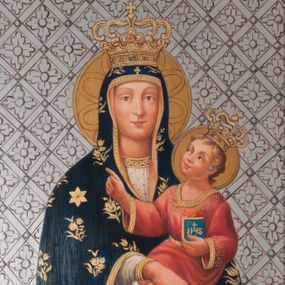 Zdjęcie nr 1: Matka Boska przedstawiona w półpostaci, ustawiona frontalnie, trzyma Dzieciątko na lewym ramieniu. Patrzy na widza, ma pogodny wyraz twarzy, jasnobrązowe oczy, prosty nos i małe usta. Dłonie składa razem, w lewej trzyma białą chustkę, w prawej ma wyprostowane dwa palce. Jest ubrana w białą suknię z pasem haftu pod szyją i granatowy maforion zdobiony kwietnymi gałązkami, lamowany złotem. Na maforionie nad czołem złoty krzyż grecki, na prawym ramieniu złota gwiazda. Dzieciątko patrzy na Matkę, prawą dłonią z wysuniętym palcem wyciąga przed siebie, w lewej trzyma książeczkę z chrystogramem na okładce. Jest ubrane w czerwoną sukienkę zdobioną haftem i lamowaną złotem, na nogach ma sandały. Na głowach obu postaci zamknięte, złote korony inkrustowane kamieniami szlachetnymi, wokół nich nimby. Tło w formie srebrnej, skośnej kratki z rozetami. 
