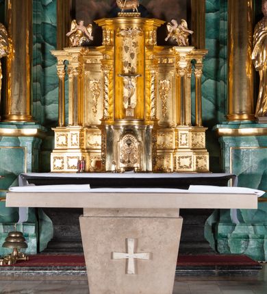 Zdjęcie nr 4: Nastawa ołtarzowa architektoniczna, jednokondygnacyjna, trójosiowa ze zwieńczeniem. 
Mensa w typie sarkofagowym, na niej rozbudowane, architektoniczne, dwukondygnacyjne, trójosiowe tabernakulum o wklęsło-wypukłej strukturze. Dolną kondygnację tabernakulum stanowi dwudzielny cokół przerwany w części środkowej na szafkę zamykaną drzwiczkami zdobionymi symbolami eucharystycznymi. Drugą kondygnację stanowi tron wystawienia – półkolista wnęka zdobiona motywem kiści winogron, z gołębicą Ducha Świętego na podniebieniu. Tron jest flankowany wnękami z dekoracją rocaille'ową oraz parami kolumn na tle pilastrów. Na dźwiganym przez kolumny rozbudowanym belkowaniu przeciwstawnie ustawione anioły kierują swój wzrok na krucyfiks. Zwieńczenie osi centralnej stanowi posążek baranka stojącego na księdze z siedmioma pieczęciami. 
Nastawa ołtarzowa jest oparta na wysokim, dwudzielnym cokole. Pole środkowe wypełnia nisza w kształcie stojącego prostokąta zamkniętego półkoliście z umieszczonym w niej obrazem Serca Pana Jezusa, powyżej którego znajduje się utworzony z motywów płomienistych rocaille'ów kartusz z koroną umieszczoną ponad dwoma skrzyżowanymi berłami. Pole centralne flankowane parami kolumn o rozbudowanych, kompozytowych kapitelach złożonych ze stylizowanych liści akantu i palmety pomiędzy wolutami, stojącymi na tle pilastrów połączonych fryzem palmetowym. Między nimi figury świętych: Katarzyny po lewej stronie i Barbary po prawej. Nastawa ujęta uszami z rocaille'u i spływów wolutowych. Kolumny dźwigają wyłamane na ich osiach belkowanie dekorowane kimationem i ząbkowaniem, z przyczółkiem przerwanym na rozbudowaną kompozycję Trójcy Świętej. W centrum przedstawienia siedzą Chrystus trzymający obiema rękami krzyż łaciński oraz Bóg Ojciec błogosławiący prawą i trzymający berło w lewej ręce. Między nimi drugi symbol władzy królewskiej – jabłko zwieńczone krzyżem, stanowiące również odniesiecie do globu ziemskiego. Postacie tronują wśród chmur, w których umieszczono główki aniołków. Powyżej nich gołębica Ducha Świętego w centrum glorii promienistej stanowiącej tło dla przedstawienia.  
 Struktura marmoryzowana na kolor zielony i niebieski; kolumny, detale, figury oraz tabernakulum złocone i srebrzone, polichromia figur w partiach ciała naturalistyczna.
