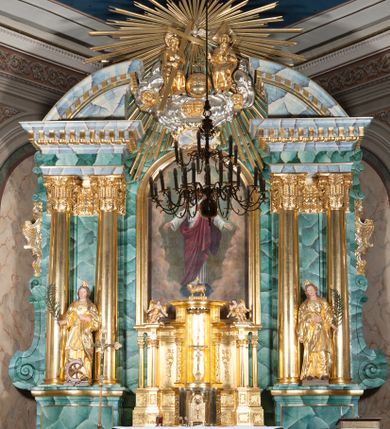 Zdjęcie nr 1: Nastawa ołtarzowa architektoniczna, jednokondygnacyjna, trójosiowa ze zwieńczeniem. 
Mensa w typie sarkofagowym, na niej rozbudowane, architektoniczne, dwukondygnacyjne, trójosiowe tabernakulum o wklęsło-wypukłej strukturze. Dolną kondygnację tabernakulum stanowi dwudzielny cokół przerwany w części środkowej na szafkę zamykaną drzwiczkami zdobionymi symbolami eucharystycznymi. Drugą kondygnację stanowi tron wystawienia – półkolista wnęka zdobiona motywem kiści winogron, z gołębicą Ducha Świętego na podniebieniu. Tron jest flankowany wnękami z dekoracją rocaille'ową oraz parami kolumn na tle pilastrów. Na dźwiganym przez kolumny rozbudowanym belkowaniu przeciwstawnie ustawione anioły kierują swój wzrok na krucyfiks. Zwieńczenie osi centralnej stanowi posążek baranka stojącego na księdze z siedmioma pieczęciami. 
Nastawa ołtarzowa jest oparta na wysokim, dwudzielnym cokole. Pole środkowe wypełnia nisza w kształcie stojącego prostokąta zamkniętego półkoliście z umieszczonym w niej obrazem Serca Pana Jezusa, powyżej którego znajduje się utworzony z motywów płomienistych rocaille'ów kartusz z koroną umieszczoną ponad dwoma skrzyżowanymi berłami. Pole centralne flankowane parami kolumn o rozbudowanych, kompozytowych kapitelach złożonych ze stylizowanych liści akantu i palmety pomiędzy wolutami, stojącymi na tle pilastrów połączonych fryzem palmetowym. Między nimi figury świętych: Katarzyny po lewej stronie i Barbary po prawej. Nastawa ujęta uszami z rocaille'u i spływów wolutowych. Kolumny dźwigają wyłamane na ich osiach belkowanie dekorowane kimationem i ząbkowaniem, z przyczółkiem przerwanym na rozbudowaną kompozycję Trójcy Świętej. W centrum przedstawienia siedzą Chrystus trzymający obiema rękami krzyż łaciński oraz Bóg Ojciec błogosławiący prawą i trzymający berło w lewej ręce. Między nimi drugi symbol władzy królewskiej – jabłko zwieńczone krzyżem, stanowiące również odniesiecie do globu ziemskiego. Postacie tronują wśród chmur, w których umieszczono główki aniołków. Powyżej nich gołębica Ducha Świętego w centrum glorii promienistej stanowiącej tło dla przedstawienia.  
 Struktura marmoryzowana na kolor zielony i niebieski; kolumny, detale, figury oraz tabernakulum złocone i srebrzone, polichromia figur w partiach ciała naturalistyczna.
