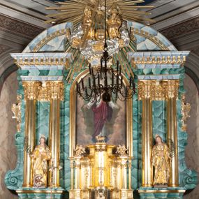Zdjęcie nr 1: Nastawa ołtarzowa architektoniczna, jednokondygnacyjna, trójosiowa ze zwieńczeniem. 
Mensa w typie sarkofagowym, na niej rozbudowane, architektoniczne, dwukondygnacyjne, trójosiowe tabernakulum o wklęsło-wypukłej strukturze. Dolną kondygnację tabernakulum stanowi dwudzielny cokół przerwany w części środkowej na szafkę zamykaną drzwiczkami zdobionymi symbolami eucharystycznymi. Drugą kondygnację stanowi tron wystawienia – półkolista wnęka zdobiona motywem kiści winogron, z gołębicą Ducha Świętego na podniebieniu. Tron jest flankowany wnękami z dekoracją rocaille'ową oraz parami kolumn na tle pilastrów. Na dźwiganym przez kolumny rozbudowanym belkowaniu przeciwstawnie ustawione anioły kierują swój wzrok na krucyfiks. Zwieńczenie osi centralnej stanowi posążek baranka stojącego na księdze z siedmioma pieczęciami. 
Nastawa ołtarzowa jest oparta na wysokim, dwudzielnym cokole. Pole środkowe wypełnia nisza w kształcie stojącego prostokąta zamkniętego półkoliście z umieszczonym w niej obrazem Serca Pana Jezusa, powyżej którego znajduje się utworzony z motywów płomienistych rocaille'ów kartusz z koroną umieszczoną ponad dwoma skrzyżowanymi berłami. Pole centralne flankowane parami kolumn o rozbudowanych, kompozytowych kapitelach złożonych ze stylizowanych liści akantu i palmety pomiędzy wolutami, stojącymi na tle pilastrów połączonych fryzem palmetowym. Między nimi figury świętych: Katarzyny po lewej stronie i Barbary po prawej. Nastawa ujęta uszami z rocaille'u i spływów wolutowych. Kolumny dźwigają wyłamane na ich osiach belkowanie dekorowane kimationem i ząbkowaniem, z przyczółkiem przerwanym na rozbudowaną kompozycję Trójcy Świętej. W centrum przedstawienia siedzą Chrystus trzymający obiema rękami krzyż łaciński oraz Bóg Ojciec błogosławiący prawą i trzymający berło w lewej ręce. Między nimi drugi symbol władzy królewskiej – jabłko zwieńczone krzyżem, stanowiące również odniesiecie do globu ziemskiego. Postacie tronują wśród chmur, w których umieszczono główki aniołków. Powyżej nich gołębica Ducha Świętego w centrum glorii promienistej stanowiącej tło dla przedstawienia.  
 Struktura marmoryzowana na kolor zielony i niebieski; kolumny, detale, figury oraz tabernakulum złocone i srebrzone, polichromia figur w partiach ciała naturalistyczna.
