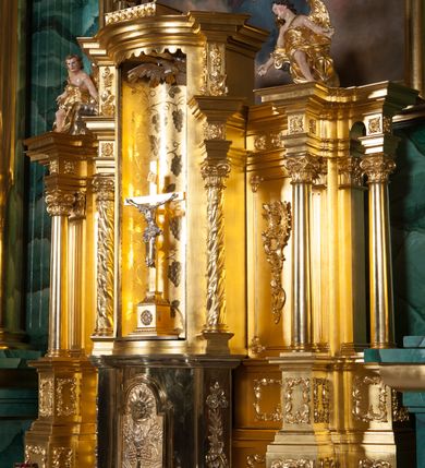 Zdjęcie nr 9: Nastawa ołtarzowa architektoniczna, jednokondygnacyjna, trójosiowa ze zwieńczeniem. 
Mensa w typie sarkofagowym, na niej rozbudowane, architektoniczne, dwukondygnacyjne, trójosiowe tabernakulum o wklęsło-wypukłej strukturze. Dolną kondygnację tabernakulum stanowi dwudzielny cokół przerwany w części środkowej na szafkę zamykaną drzwiczkami zdobionymi symbolami eucharystycznymi. Drugą kondygnację stanowi tron wystawienia – półkolista wnęka zdobiona motywem kiści winogron, z gołębicą Ducha Świętego na podniebieniu. Tron jest flankowany wnękami z dekoracją rocaille'ową oraz parami kolumn na tle pilastrów. Na dźwiganym przez kolumny rozbudowanym belkowaniu przeciwstawnie ustawione anioły kierują swój wzrok na krucyfiks. Zwieńczenie osi centralnej stanowi posążek baranka stojącego na księdze z siedmioma pieczęciami. 
Nastawa ołtarzowa jest oparta na wysokim, dwudzielnym cokole. Pole środkowe wypełnia nisza w kształcie stojącego prostokąta zamkniętego półkoliście z umieszczonym w niej obrazem Serca Pana Jezusa, powyżej którego znajduje się utworzony z motywów płomienistych rocaille'ów kartusz z koroną umieszczoną ponad dwoma skrzyżowanymi berłami. Pole centralne flankowane parami kolumn o rozbudowanych, kompozytowych kapitelach złożonych ze stylizowanych liści akantu i palmety pomiędzy wolutami, stojącymi na tle pilastrów połączonych fryzem palmetowym. Między nimi figury świętych: Katarzyny po lewej stronie i Barbary po prawej. Nastawa ujęta uszami z rocaille'u i spływów wolutowych. Kolumny dźwigają wyłamane na ich osiach belkowanie dekorowane kimationem i ząbkowaniem, z przyczółkiem przerwanym na rozbudowaną kompozycję Trójcy Świętej. W centrum przedstawienia siedzą Chrystus trzymający obiema rękami krzyż łaciński oraz Bóg Ojciec błogosławiący prawą i trzymający berło w lewej ręce. Między nimi drugi symbol władzy królewskiej – jabłko zwieńczone krzyżem, stanowiące również odniesiecie do globu ziemskiego. Postacie tronują wśród chmur, w których umieszczono główki aniołków. Powyżej nich gołębica Ducha Świętego w centrum glorii promienistej stanowiącej tło dla przedstawienia.  
 Struktura marmoryzowana na kolor zielony i niebieski; kolumny, detale, figury oraz tabernakulum złocone i srebrzone, polichromia figur w partiach ciała naturalistyczna.
