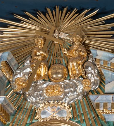 Zdjęcie nr 7: Nastawa ołtarzowa architektoniczna, jednokondygnacyjna, trójosiowa ze zwieńczeniem. 
Mensa w typie sarkofagowym, na niej rozbudowane, architektoniczne, dwukondygnacyjne, trójosiowe tabernakulum o wklęsło-wypukłej strukturze. Dolną kondygnację tabernakulum stanowi dwudzielny cokół przerwany w części środkowej na szafkę zamykaną drzwiczkami zdobionymi symbolami eucharystycznymi. Drugą kondygnację stanowi tron wystawienia – półkolista wnęka zdobiona motywem kiści winogron, z gołębicą Ducha Świętego na podniebieniu. Tron jest flankowany wnękami z dekoracją rocaille&#039;ową oraz parami kolumn na tle pilastrów. Na dźwiganym przez kolumny rozbudowanym belkowaniu przeciwstawnie ustawione anioły kierują swój wzrok na krucyfiks. Zwieńczenie osi centralnej stanowi posążek baranka stojącego na księdze z siedmioma pieczęciami. 
Nastawa ołtarzowa jest oparta na wysokim, dwudzielnym cokole. Pole środkowe wypełnia nisza w kształcie stojącego prostokąta zamkniętego półkoliście z umieszczonym w niej obrazem Serca Pana Jezusa, powyżej którego znajduje się utworzony z motywów płomienistych rocaille&#039;ów kartusz z koroną umieszczoną ponad dwoma skrzyżowanymi berłami. Pole centralne flankowane parami kolumn o rozbudowanych, kompozytowych kapitelach złożonych ze stylizowanych liści akantu i palmety pomiędzy wolutami, stojącymi na tle pilastrów połączonych fryzem palmetowym. Między nimi figury świętych: Katarzyny po lewej stronie i Barbary po prawej. Nastawa ujęta uszami z rocaille&#039;u i spływów wolutowych. Kolumny dźwigają wyłamane na ich osiach belkowanie dekorowane kimationem i ząbkowaniem, z przyczółkiem przerwanym na rozbudowaną kompozycję Trójcy Świętej. W centrum przedstawienia siedzą Chrystus trzymający obiema rękami krzyż łaciński oraz Bóg Ojciec błogosławiący prawą i trzymający berło w lewej ręce. Między nimi drugi symbol władzy królewskiej – jabłko zwieńczone krzyżem, stanowiące również odniesiecie do globu ziemskiego. Postacie tronują wśród chmur, w których umieszczono główki aniołków. Powyżej nich gołębica Ducha Świętego w centrum glorii promienistej stanowiącej tło dla przedstawienia.  
 Struktura marmoryzowana na kolor zielony i niebieski; kolumny, detale, figury oraz tabernakulum złocone i srebrzone, polichromia figur w partiach ciała naturalistyczna.
