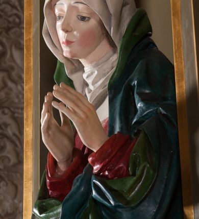 Zdjęcie nr 3: Rzeźba pełna, na cokole. Maria przedstawiona w całej postaci, w pozycji stojącej w ujęciu frontalnym. Ręce składa do modlitwy, głowę ma pochyloną na lewe ramię, spogląda w dół. Na jej łagodnej twarzy maluje się smutek, spod uniesionych brwi spoglądają duże, szare oczy o zewnętrznych kącikach skierowany w dół, nos mały, usta drobne, czerwone; na policzkach rumieńce. 
Maria jest ubrana w długą, czerwoną suknię. Głowę okrywa  biały welon, a dekolt tego samego koloru podwika. Na suknię ma narzucony niebieski płaszcz z zielonym podbiciem, który układa się w gęste, głębokie fałdy i wywija w formę kołnierza, wokół dłoni oraz tworzy małą rozetkę przy prawej stopie. Spod sukni wystają szpiczaste pantofelki. Polichromia w partiach ciała naturalistyczna. 
