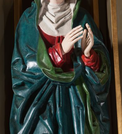 Zdjęcie nr 5: Rzeźba pełna, na cokole. Maria przedstawiona w całej postaci, w pozycji stojącej w ujęciu frontalnym. Ręce składa do modlitwy, głowę ma pochyloną na lewe ramię, spogląda w dół. Na jej łagodnej twarzy maluje się smutek, spod uniesionych brwi spoglądają duże, szare oczy o zewnętrznych kącikach skierowany w dół, nos mały, usta drobne, czerwone; na policzkach rumieńce. 
Maria jest ubrana w długą, czerwoną suknię. Głowę okrywa  biały welon, a dekolt tego samego koloru podwika. Na suknię ma narzucony niebieski płaszcz z zielonym podbiciem, który układa się w gęste, głębokie fałdy i wywija w formę kołnierza, wokół dłoni oraz tworzy małą rozetkę przy prawej stopie. Spod sukni wystają szpiczaste pantofelki. Polichromia w partiach ciała naturalistyczna. 
