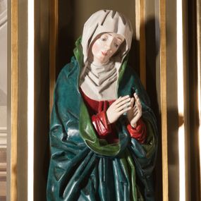 Zdjęcie nr 1: Rzeźba pełna, na cokole. Maria przedstawiona w całej postaci, w pozycji stojącej w ujęciu frontalnym. Ręce składa do modlitwy, głowę ma pochyloną na lewe ramię, spogląda w dół. Na jej łagodnej twarzy maluje się smutek, spod uniesionych brwi spoglądają duże, szare oczy o zewnętrznych kącikach skierowany w dół, nos mały, usta drobne, czerwone; na policzkach rumieńce. 
Maria jest ubrana w długą, czerwoną suknię. Głowę okrywa  biały welon, a dekolt tego samego koloru podwika. Na suknię ma narzucony niebieski płaszcz z zielonym podbiciem, który układa się w gęste, głębokie fałdy i wywija w formę kołnierza, wokół dłoni oraz tworzy małą rozetkę przy prawej stopie. Spod sukni wystają szpiczaste pantofelki. Polichromia w partiach ciała naturalistyczna. 
