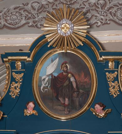 Zdjęcie nr 4: Ołtarz przyścienny, architektoniczny, jednoosiowy, jednokondygnacjowy ze zwieńczeniem. Retabulum ustawione na wysokim, dwukondygnacjowym  cokole o wyższej kondygnacji dolnej, z dwoma postumentami wyodrębnionymi po bokach;  powierzchnia cokołu dekorowana płycinami w kształcie prostokątów. Cokół przerwany w środku drzwiami do zakrystii ze skrzydłami w formie pionowych prostokątów podzielonych – każde skrzydło – na osiem mniejszych pól. Pole centralne ołtarza wypełnia obraz z przedstawieniem św. Kingi  odkrywającej złoża soli. Obraz ujęty w ramę w kształcie pionowego prostokąta zamkniętego łukiem wklęsło-wypukłym z uskokami; poniżej wstęga z inskrypcją „S(ANCTA) CUNEGUNDA ORA PRO NOBIS”. Pole z obrazem flankowane jest parami kolumn korynckich, z których zewnętrzne są wysunięte do przodu. Przed nie występują do przodu konsole na których ustawiono rzeźby św. Wojciecha i św. Stanisława. Kolumny dźwigają belkowanie przełamane na ich osiach i wygięte ku górze na linii płytkiego łuku odcinkowego powyżej obrazu;  pośrodku łuku dekoracja w formie dużej muszli. Na fryzie przełamanych fragmentów belkowania plakiety utworzone z dekoracji roślinnej; na osiach wewnętrznych kolumn, ponad belkowaniem, wazony z kwiatami. Ponad kolumnami zewnętrznymi i belkowaniem widoczne rozsunięte odcinki półkolistego, pękniętego przyczółka, na których posadowiono figurki aniołków. Pomiędzy odcinkami przyczółka zwieńczenie o formie ścianki w ogólnym kształcie zbliżonej do trapezu, o wklęsłych bokach zakończonych u dołu wolutami,  zamkniętej łukiem nadwieszonym; ścianka od góry zwieńczona częściowo niepełnym belkowaniem. Owalne pole pośrodku zwieńczenia wypełnia obraz z przedstawieniem św. Floriana; po bokach ramy rozmieszczone główki anielskie i plakiety z dekoracją roślinną. Ponad obrazem, na tle gzymsu belkowania od góry zamykającego zwieńczenie, widoczny medalion z monogramem Chrystusa otoczony obłokami, na tle glorii promienistej.  
Struktura retabulum malowana na kolor niebieski; profile, kolumny, ornamenty, detale złocone; figury oraz gloria złocone i srebrzone.
