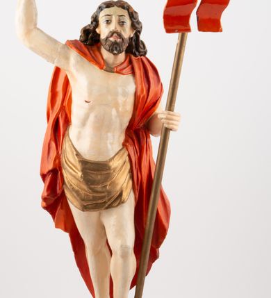 Zdjęcie nr 2: Rzeźba pełnoplastyczna, z tyłu opracowana, ustawiona na niewysokim cokole. Postać zwrócona frontalnie do widza, w kontrapoście, o esowato wygiętej sylwetce. W lewej ręce trzymał chorągiew, prawą unosi wysoko do góry w geście błogosławieństwa. Ciało o wyraźnie rzeźbionej muskulaturze z zaznaczonymi śladami męki. Twarz szczupła, o podkreślonej linii kości policzkowych i długim, prostym nosie, z dużymi oczami. Twarz okolona zarostem, włosy długie, gęste, z przedziałkiem na środku głowy, opadające na plecy. Przez biodra przepasane złote perizonium; pod szyją zapięty czerwony płaszcz opadający na plecy i lewe ramię. Karnacja ciała naturalistyczna, perizonium złocone.
