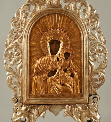 Zdjęcie nr 1: Pole obrazowe feretronu w formie stojącego prostokąta zamkniętego łukiem półkolistym, w profilowanej ramie, ujętej wicią utworzoną z liści akantu i rozet, formujących w dolnych narożach głowy gryfów z otworami na drążki, które spoczywają na profilowanych cokolikach. Feretron zwieńczony fragmentem cokołu, z jednej strony o kanelowanym trzonie, z drugiej ujętego akantem.
Na awersie płaskorzeźbiony wizerunek św. Anny Samotrzeć z Marią i Dzieciątkiem, którego postacie mają malowane twarze, dłonie i stopy. W centrum św. Anna, w pozycji siedzącej, na cokole, ukazana frontalnie. Lewą ręką przytrzymuje na kolanie Dzieciątko, prawą obejmuje stojącą obok Marię. Anna ma szczupłą twarz, o dojrzałych rysach, migdałowatych oczach, prostym nosie i pełnych ustach. Ubrana jest w złoconą suknię, na głowę i ramiona ma narzucony złocony płaszcz, zawiązany pod szyją, na głowie ma koronę zamkniętą. Dzieciątko w pozycji siedzącej, zwrócone w trzech czwartych w lewo, z głową skierowaną w przeciwna stronę, obie, ugięte ręce wyciąga w lewo. Twarz ma trójkątną, o migdałowatych oczach, małym nosie i ustach, okoloną jasnobrązowymi włosami. Ubrane jest w złoconą tunikę, na głowie ma złoconą koronę zamkniętą. Po prawej stronie Anny stoi Maria zwrócona profilem w lewo, obie ręce wyciąga przed siebie, prawą wskazuje na Chrystusa. Twarz ma szczupłą, o młodzieńczych rysach, wąskich oczach, małym nosie i ustach. Ubrana jest w złoconą suknię oraz złocony płaszcz zarzucony na głowę i ramiona, na głowie ma złoconą, zamkniętą koronę. Postacie ukazane są na złoconym tle glorii promienistej. 
Na rewersie feretronu płaskorzeźbiony wizerunek Matki Boskiej z Dzieciątkiem, na którym postacie mają malowane twarze, dłonie i stopy. Matka Boska ukazana w półpostaci, frontalnie, lewą ręką podtrzymuje Dzieciątko, prawą, ugiętą wskazuje na nie. Twarz ma pociągłą i szczupłą, o wąskich, migdałowatych oczach, długim, wąskim nosie i małych, pełnych ustach, o ciemnej karnacji, ze śladami dwóch cięć na prawym policzku. Ubrana jest w złoconą suknię i złocony maforion zarzucony na głowę i ramiona. Na głowie ma koronę otwartą, wokół niej nimb. Dzieciątko w pozycji siedzącej, zwrócone w trzech czwartych w prawo, lewą ręką przytrzymuje na kolanach księgę, prawą unosi w geście błogosławieństwa. Twarz o ciemnej karnacji, okrągła, o dużych oczach, krótkim nosie i pełnych ustach, okolona ciemnymi, krótkimi włosami. Ubrane jest w złoconą tunikę, na głowie ma złoconą koronę otwartą, wokół niej nimb. Postacie ukazane są na złoconym tle glorii promienistej. U spodu obrazu banderola z napisem: „POD TWOJA OBRONE UCIEKAMY SIE S[WIĘTA] B[OŻA] R[ODZICIELKO]”.
