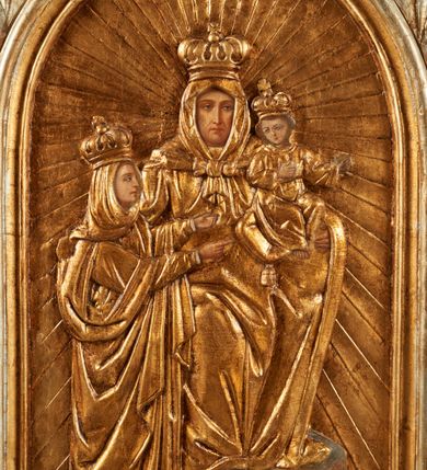 Zdjęcie nr 4: Pole obrazowe feretronu w formie stojącego prostokąta zamkniętego łukiem półkolistym, w profilowanej ramie, ujętej wicią utworzoną z liści akantu i rozet, formujących w dolnych narożach głowy gryfów z otworami na drążki, które spoczywają na profilowanych cokolikach. Feretron zwieńczony fragmentem cokołu, z jednej strony o kanelowanym trzonie, z drugiej ujętego akantem.
Na awersie płaskorzeźbiony wizerunek św. Anny Samotrzeć z Marią i Dzieciątkiem, którego postacie mają malowane twarze, dłonie i stopy. W centrum św. Anna, w pozycji siedzącej, na cokole, ukazana frontalnie. Lewą ręką przytrzymuje na kolanie Dzieciątko, prawą obejmuje stojącą obok Marię. Anna ma szczupłą twarz, o dojrzałych rysach, migdałowatych oczach, prostym nosie i pełnych ustach. Ubrana jest w złoconą suknię, na głowę i ramiona ma narzucony złocony płaszcz, zawiązany pod szyją, na głowie ma koronę zamkniętą. Dzieciątko w pozycji siedzącej, zwrócone w trzech czwartych w lewo, z głową skierowaną w przeciwna stronę, obie, ugięte ręce wyciąga w lewo. Twarz ma trójkątną, o migdałowatych oczach, małym nosie i ustach, okoloną jasnobrązowymi włosami. Ubrane jest w złoconą tunikę, na głowie ma złoconą koronę zamkniętą. Po prawej stronie Anny stoi Maria zwrócona profilem w lewo, obie ręce wyciąga przed siebie, prawą wskazuje na Chrystusa. Twarz ma szczupłą, o młodzieńczych rysach, wąskich oczach, małym nosie i ustach. Ubrana jest w złoconą suknię oraz złocony płaszcz zarzucony na głowę i ramiona, na głowie ma złoconą, zamkniętą koronę. Postacie ukazane są na złoconym tle glorii promienistej. 
Na rewersie feretronu płaskorzeźbiony wizerunek Matki Boskiej z Dzieciątkiem, na którym postacie mają malowane twarze, dłonie i stopy. Matka Boska ukazana w półpostaci, frontalnie, lewą ręką podtrzymuje Dzieciątko, prawą, ugiętą wskazuje na nie. Twarz ma pociągłą i szczupłą, o wąskich, migdałowatych oczach, długim, wąskim nosie i małych, pełnych ustach, o ciemnej karnacji, ze śladami dwóch cięć na prawym policzku. Ubrana jest w złoconą suknię i złocony maforion zarzucony na głowę i ramiona. Na głowie ma koronę otwartą, wokół niej nimb. Dzieciątko w pozycji siedzącej, zwrócone w trzech czwartych w prawo, lewą ręką przytrzymuje na kolanach księgę, prawą unosi w geście błogosławieństwa. Twarz o ciemnej karnacji, okrągła, o dużych oczach, krótkim nosie i pełnych ustach, okolona ciemnymi, krótkimi włosami. Ubrane jest w złoconą tunikę, na głowie ma złoconą koronę otwartą, wokół niej nimb. Postacie ukazane są na złoconym tle glorii promienistej. U spodu obrazu banderola z napisem: „POD TWOJA OBRONE UCIEKAMY SIE S[WIĘTA] B[OŻA] R[ODZICIELKO]”.
