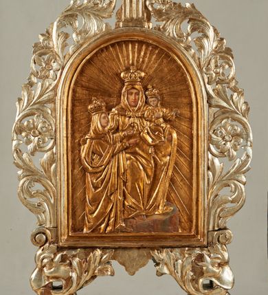 Zdjęcie nr 2: Pole obrazowe feretronu w formie stojącego prostokąta zamkniętego łukiem półkolistym, w profilowanej ramie, ujętej wicią utworzoną z liści akantu i rozet, formujących w dolnych narożach głowy gryfów z otworami na drążki, które spoczywają na profilowanych cokolikach. Feretron zwieńczony fragmentem cokołu, z jednej strony o kanelowanym trzonie, z drugiej ujętego akantem.
Na awersie płaskorzeźbiony wizerunek św. Anny Samotrzeć z Marią i Dzieciątkiem, którego postacie mają malowane twarze, dłonie i stopy. W centrum św. Anna, w pozycji siedzącej, na cokole, ukazana frontalnie. Lewą ręką przytrzymuje na kolanie Dzieciątko, prawą obejmuje stojącą obok Marię. Anna ma szczupłą twarz, o dojrzałych rysach, migdałowatych oczach, prostym nosie i pełnych ustach. Ubrana jest w złoconą suknię, na głowę i ramiona ma narzucony złocony płaszcz, zawiązany pod szyją, na głowie ma koronę zamkniętą. Dzieciątko w pozycji siedzącej, zwrócone w trzech czwartych w lewo, z głową skierowaną w przeciwna stronę, obie, ugięte ręce wyciąga w lewo. Twarz ma trójkątną, o migdałowatych oczach, małym nosie i ustach, okoloną jasnobrązowymi włosami. Ubrane jest w złoconą tunikę, na głowie ma złoconą koronę zamkniętą. Po prawej stronie Anny stoi Maria zwrócona profilem w lewo, obie ręce wyciąga przed siebie, prawą wskazuje na Chrystusa. Twarz ma szczupłą, o młodzieńczych rysach, wąskich oczach, małym nosie i ustach. Ubrana jest w złoconą suknię oraz złocony płaszcz zarzucony na głowę i ramiona, na głowie ma złoconą, zamkniętą koronę. Postacie ukazane są na złoconym tle glorii promienistej. 
Na rewersie feretronu płaskorzeźbiony wizerunek Matki Boskiej z Dzieciątkiem, na którym postacie mają malowane twarze, dłonie i stopy. Matka Boska ukazana w półpostaci, frontalnie, lewą ręką podtrzymuje Dzieciątko, prawą, ugiętą wskazuje na nie. Twarz ma pociągłą i szczupłą, o wąskich, migdałowatych oczach, długim, wąskim nosie i małych, pełnych ustach, o ciemnej karnacji, ze śladami dwóch cięć na prawym policzku. Ubrana jest w złoconą suknię i złocony maforion zarzucony na głowę i ramiona. Na głowie ma koronę otwartą, wokół niej nimb. Dzieciątko w pozycji siedzącej, zwrócone w trzech czwartych w prawo, lewą ręką przytrzymuje na kolanach księgę, prawą unosi w geście błogosławieństwa. Twarz o ciemnej karnacji, okrągła, o dużych oczach, krótkim nosie i pełnych ustach, okolona ciemnymi, krótkimi włosami. Ubrane jest w złoconą tunikę, na głowie ma złoconą koronę otwartą, wokół niej nimb. Postacie ukazane są na złoconym tle glorii promienistej. U spodu obrazu banderola z napisem: „POD TWOJA OBRONE UCIEKAMY SIE S[WIĘTA] B[OŻA] R[ODZICIELKO]”.
