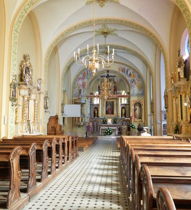 Zdjęcie nr 59: Kościół murowany, orientowany, jednonawowy, trójprzęsłowy, z transeptem i jednoprzęsłowym, węższym i niższym prezbiterium zamkniętym trójbocznie. Między nawą a transeptem po obu stronach znajdują się kruchty, do prezbiterium od strony północnej dostawiona kruchta złożona z dwóch lokalności. Ściany są rozczłonkowane filarami, tworzącymi płytkie arkadowe wnęki. Między nawą a prezbiterium arkada tęczowa. Sklepienie krzyżowe na gurtach spływających na filary. Prezbiterium oświetlają wąskie, prostokątne okna zamknięte ostrołukowo, w nawie i w transepcie znajdują się prostokątne okna prostokątne zamknięte półkoliście, w ścianie frontowej w dolnej części okna prostokątne zamknięte półkoliście, a w górnej podwójne okna prostokątne. Fasada ujęta dwiema narożnymi szkarpami, zwieńczona trójkątnie. Do niej dostawiona kruchta z dwuspadowym daszkiem i wejściem w kształcie prostokąta zamkniętego półkoliście. W kamiennej fasadzie znajdują się dołem okna prostokątne, zamknięte półkoliście, a górą  prostokątne, biforialne okna z nadprożem łukowatym wykonanym z cegły. Szczyt ceglany, podzielony na trzy strefy kamiennym wątkiem, z pięcioma wnękami prostokątnymi, zamkniętymi półkoliście, z wąskimi otworami w dolnej strefie i z owalnym oknem w drugiej. Elewacje boczne nawy ujęte skarpami. Dachy dwuspadowe, kryte dachówką, z wieżyczką na sygnaturkę.         