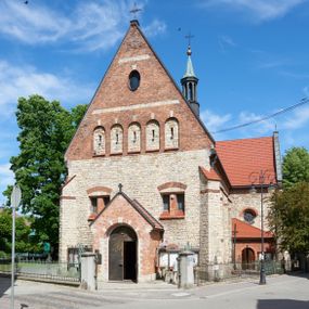Zdjęcie nr 1: Kościół murowany, orientowany, jednonawowy, trójprzęsłowy, z transeptem i jednoprzęsłowym, węższym i niższym prezbiterium zamkniętym trójbocznie. Między nawą a transeptem po obu stronach znajdują się kruchty, do prezbiterium od strony północnej dostawiona kruchta złożona z dwóch lokalności. Ściany są rozczłonkowane filarami, tworzącymi płytkie arkadowe wnęki. Między nawą a prezbiterium arkada tęczowa. Sklepienie krzyżowe na gurtach spływających na filary. Prezbiterium oświetlają wąskie, prostokątne okna zamknięte ostrołukowo, w nawie i w transepcie znajdują się prostokątne okna prostokątne zamknięte półkoliście, w ścianie frontowej w dolnej części okna prostokątne zamknięte półkoliście, a w górnej podwójne okna prostokątne. Fasada ujęta dwiema narożnymi szkarpami, zwieńczona trójkątnie. Do niej dostawiona kruchta z dwuspadowym daszkiem i wejściem w kształcie prostokąta zamkniętego półkoliście. W kamiennej fasadzie znajdują się dołem okna prostokątne, zamknięte półkoliście, a górą  prostokątne, biforialne okna z nadprożem łukowatym wykonanym z cegły. Szczyt ceglany, podzielony na trzy strefy kamiennym wątkiem, z pięcioma wnękami prostokątnymi, zamkniętymi półkoliście, z wąskimi otworami w dolnej strefie i z owalnym oknem w drugiej. Elewacje boczne nawy ujęte skarpami. Dachy dwuspadowe, kryte dachówką, z wieżyczką na sygnaturkę.         