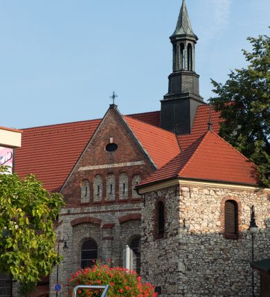 Zdjęcie nr 63: Kościół murowany, orientowany, jednonawowy, trójprzęsłowy, z transeptem i jednoprzęsłowym, węższym i niższym prezbiterium zamkniętym trójbocznie. Między nawą a transeptem po obu stronach znajdują się kruchty, do prezbiterium od strony północnej dostawiona kruchta złożona z dwóch lokalności. Ściany są rozczłonkowane filarami, tworzącymi płytkie arkadowe wnęki. Między nawą a prezbiterium arkada tęczowa. Sklepienie krzyżowe na gurtach spływających na filary. Prezbiterium oświetlają wąskie, prostokątne okna zamknięte ostrołukowo, w nawie i w transepcie znajdują się prostokątne okna prostokątne zamknięte półkoliście, w ścianie frontowej w dolnej części okna prostokątne zamknięte półkoliście, a w górnej podwójne okna prostokątne. Fasada ujęta dwiema narożnymi szkarpami, zwieńczona trójkątnie. Do niej dostawiona kruchta z dwuspadowym daszkiem i wejściem w kształcie prostokąta zamkniętego półkoliście. W kamiennej fasadzie znajdują się dołem okna prostokątne, zamknięte półkoliście, a górą  prostokątne, biforialne okna z nadprożem łukowatym wykonanym z cegły. Szczyt ceglany, podzielony na trzy strefy kamiennym wątkiem, z pięcioma wnękami prostokątnymi, zamkniętymi półkoliście, z wąskimi otworami w dolnej strefie i z owalnym oknem w drugiej. Elewacje boczne nawy ujęte skarpami. Dachy dwuspadowe, kryte dachówką, z wieżyczką na sygnaturkę.         