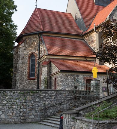 Zdjęcie nr 7: Kościół murowany, orientowany, jednonawowy, trójprzęsłowy, z transeptem i jednoprzęsłowym, węższym i niższym prezbiterium zamkniętym trójbocznie. Między nawą a transeptem po obu stronach znajdują się kruchty, do prezbiterium od strony północnej dostawiona kruchta złożona z dwóch lokalności. Ściany są rozczłonkowane filarami, tworzącymi płytkie arkadowe wnęki. Między nawą a prezbiterium arkada tęczowa. Sklepienie krzyżowe na gurtach spływających na filary. Prezbiterium oświetlają wąskie, prostokątne okna zamknięte ostrołukowo, w nawie i w transepcie znajdują się prostokątne okna prostokątne zamknięte półkoliście, w ścianie frontowej w dolnej części okna prostokątne zamknięte półkoliście, a w górnej podwójne okna prostokątne. Fasada ujęta dwiema narożnymi szkarpami, zwieńczona trójkątnie. Do niej dostawiona kruchta z dwuspadowym daszkiem i wejściem w kształcie prostokąta zamkniętego półkoliście. W kamiennej fasadzie znajdują się dołem okna prostokątne, zamknięte półkoliście, a górą  prostokątne, biforialne okna z nadprożem łukowatym wykonanym z cegły. Szczyt ceglany, podzielony na trzy strefy kamiennym wątkiem, z pięcioma wnękami prostokątnymi, zamkniętymi półkoliście, z wąskimi otworami w dolnej strefie i z owalnym oknem w drugiej. Elewacje boczne nawy ujęte skarpami. Dachy dwuspadowe, kryte dachówką, z wieżyczką na sygnaturkę.         