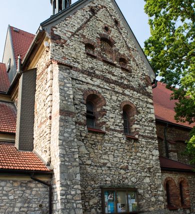 Zdjęcie nr 9: Kościół murowany, orientowany, jednonawowy, trójprzęsłowy, z transeptem i jednoprzęsłowym, węższym i niższym prezbiterium zamkniętym trójbocznie. Między nawą a transeptem po obu stronach znajdują się kruchty, do prezbiterium od strony północnej dostawiona kruchta złożona z dwóch lokalności. Ściany są rozczłonkowane filarami, tworzącymi płytkie arkadowe wnęki. Między nawą a prezbiterium arkada tęczowa. Sklepienie krzyżowe na gurtach spływających na filary. Prezbiterium oświetlają wąskie, prostokątne okna zamknięte ostrołukowo, w nawie i w transepcie znajdują się prostokątne okna prostokątne zamknięte półkoliście, w ścianie frontowej w dolnej części okna prostokątne zamknięte półkoliście, a w górnej podwójne okna prostokątne. Fasada ujęta dwiema narożnymi szkarpami, zwieńczona trójkątnie. Do niej dostawiona kruchta z dwuspadowym daszkiem i wejściem w kształcie prostokąta zamkniętego półkoliście. W kamiennej fasadzie znajdują się dołem okna prostokątne, zamknięte półkoliście, a górą  prostokątne, biforialne okna z nadprożem łukowatym wykonanym z cegły. Szczyt ceglany, podzielony na trzy strefy kamiennym wątkiem, z pięcioma wnękami prostokątnymi, zamkniętymi półkoliście, z wąskimi otworami w dolnej strefie i z owalnym oknem w drugiej. Elewacje boczne nawy ujęte skarpami. Dachy dwuspadowe, kryte dachówką, z wieżyczką na sygnaturkę.         