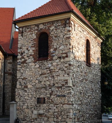 Zdjęcie nr 5: Kościół murowany, orientowany, jednonawowy, trójprzęsłowy, z transeptem i jednoprzęsłowym, węższym i niższym prezbiterium zamkniętym trójbocznie. Między nawą a transeptem po obu stronach znajdują się kruchty, do prezbiterium od strony północnej dostawiona kruchta złożona z dwóch lokalności. Ściany są rozczłonkowane filarami, tworzącymi płytkie arkadowe wnęki. Między nawą a prezbiterium arkada tęczowa. Sklepienie krzyżowe na gurtach spływających na filary. Prezbiterium oświetlają wąskie, prostokątne okna zamknięte ostrołukowo, w nawie i w transepcie znajdują się prostokątne okna prostokątne zamknięte półkoliście, w ścianie frontowej w dolnej części okna prostokątne zamknięte półkoliście, a w górnej podwójne okna prostokątne. Fasada ujęta dwiema narożnymi szkarpami, zwieńczona trójkątnie. Do niej dostawiona kruchta z dwuspadowym daszkiem i wejściem w kształcie prostokąta zamkniętego półkoliście. W kamiennej fasadzie znajdują się dołem okna prostokątne, zamknięte półkoliście, a górą  prostokątne, biforialne okna z nadprożem łukowatym wykonanym z cegły. Szczyt ceglany, podzielony na trzy strefy kamiennym wątkiem, z pięcioma wnękami prostokątnymi, zamkniętymi półkoliście, z wąskimi otworami w dolnej strefie i z owalnym oknem w drugiej. Elewacje boczne nawy ujęte skarpami. Dachy dwuspadowe, kryte dachówką, z wieżyczką na sygnaturkę.         