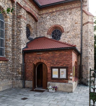 Zdjęcie nr 16: Kościół murowany, orientowany, jednonawowy, trójprzęsłowy, z transeptem i jednoprzęsłowym, węższym i niższym prezbiterium zamkniętym trójbocznie. Między nawą a transeptem po obu stronach znajdują się kruchty, do prezbiterium od strony północnej dostawiona kruchta złożona z dwóch lokalności. Ściany są rozczłonkowane filarami, tworzącymi płytkie arkadowe wnęki. Między nawą a prezbiterium arkada tęczowa. Sklepienie krzyżowe na gurtach spływających na filary. Prezbiterium oświetlają wąskie, prostokątne okna zamknięte ostrołukowo, w nawie i w transepcie znajdują się prostokątne okna prostokątne zamknięte półkoliście, w ścianie frontowej w dolnej części okna prostokątne zamknięte półkoliście, a w górnej podwójne okna prostokątne. Fasada ujęta dwiema narożnymi szkarpami, zwieńczona trójkątnie. Do niej dostawiona kruchta z dwuspadowym daszkiem i wejściem w kształcie prostokąta zamkniętego półkoliście. W kamiennej fasadzie znajdują się dołem okna prostokątne, zamknięte półkoliście, a górą  prostokątne, biforialne okna z nadprożem łukowatym wykonanym z cegły. Szczyt ceglany, podzielony na trzy strefy kamiennym wątkiem, z pięcioma wnękami prostokątnymi, zamkniętymi półkoliście, z wąskimi otworami w dolnej strefie i z owalnym oknem w drugiej. Elewacje boczne nawy ujęte skarpami. Dachy dwuspadowe, kryte dachówką, z wieżyczką na sygnaturkę.         