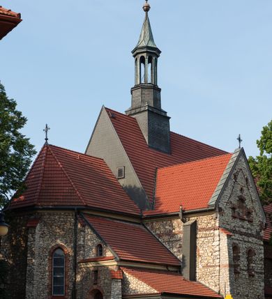 Zdjęcie nr 17: Kościół murowany, orientowany, jednonawowy, trójprzęsłowy, z transeptem i jednoprzęsłowym, węższym i niższym prezbiterium zamkniętym trójbocznie. Między nawą a transeptem po obu stronach znajdują się kruchty, do prezbiterium od strony północnej dostawiona kruchta złożona z dwóch lokalności. Ściany są rozczłonkowane filarami, tworzącymi płytkie arkadowe wnęki. Między nawą a prezbiterium arkada tęczowa. Sklepienie krzyżowe na gurtach spływających na filary. Prezbiterium oświetlają wąskie, prostokątne okna zamknięte ostrołukowo, w nawie i w transepcie znajdują się prostokątne okna prostokątne zamknięte półkoliście, w ścianie frontowej w dolnej części okna prostokątne zamknięte półkoliście, a w górnej podwójne okna prostokątne. Fasada ujęta dwiema narożnymi szkarpami, zwieńczona trójkątnie. Do niej dostawiona kruchta z dwuspadowym daszkiem i wejściem w kształcie prostokąta zamkniętego półkoliście. W kamiennej fasadzie znajdują się dołem okna prostokątne, zamknięte półkoliście, a górą  prostokątne, biforialne okna z nadprożem łukowatym wykonanym z cegły. Szczyt ceglany, podzielony na trzy strefy kamiennym wątkiem, z pięcioma wnękami prostokątnymi, zamkniętymi półkoliście, z wąskimi otworami w dolnej strefie i z owalnym oknem w drugiej. Elewacje boczne nawy ujęte skarpami. Dachy dwuspadowe, kryte dachówką, z wieżyczką na sygnaturkę.         