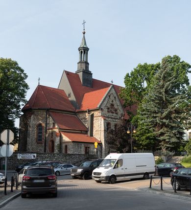 Zdjęcie nr 18: Kościół murowany, orientowany, jednonawowy, trójprzęsłowy, z transeptem i jednoprzęsłowym, węższym i niższym prezbiterium zamkniętym trójbocznie. Między nawą a transeptem po obu stronach znajdują się kruchty, do prezbiterium od strony północnej dostawiona kruchta złożona z dwóch lokalności. Ściany są rozczłonkowane filarami, tworzącymi płytkie arkadowe wnęki. Między nawą a prezbiterium arkada tęczowa. Sklepienie krzyżowe na gurtach spływających na filary. Prezbiterium oświetlają wąskie, prostokątne okna zamknięte ostrołukowo, w nawie i w transepcie znajdują się prostokątne okna prostokątne zamknięte półkoliście, w ścianie frontowej w dolnej części okna prostokątne zamknięte półkoliście, a w górnej podwójne okna prostokątne. Fasada ujęta dwiema narożnymi szkarpami, zwieńczona trójkątnie. Do niej dostawiona kruchta z dwuspadowym daszkiem i wejściem w kształcie prostokąta zamkniętego półkoliście. W kamiennej fasadzie znajdują się dołem okna prostokątne, zamknięte półkoliście, a górą  prostokątne, biforialne okna z nadprożem łukowatym wykonanym z cegły. Szczyt ceglany, podzielony na trzy strefy kamiennym wątkiem, z pięcioma wnękami prostokątnymi, zamkniętymi półkoliście, z wąskimi otworami w dolnej strefie i z owalnym oknem w drugiej. Elewacje boczne nawy ujęte skarpami. Dachy dwuspadowe, kryte dachówką, z wieżyczką na sygnaturkę.         