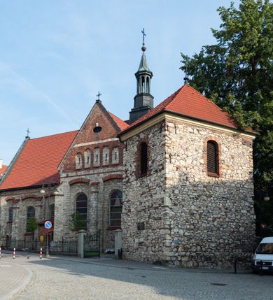 Zdjęcie nr 28: Kościół murowany, orientowany, jednonawowy, trójprzęsłowy, z transeptem i jednoprzęsłowym, węższym i niższym prezbiterium zamkniętym trójbocznie. Między nawą a transeptem po obu stronach znajdują się kruchty, do prezbiterium od strony północnej dostawiona kruchta złożona z dwóch lokalności. Ściany są rozczłonkowane filarami, tworzącymi płytkie arkadowe wnęki. Między nawą a prezbiterium arkada tęczowa. Sklepienie krzyżowe na gurtach spływających na filary. Prezbiterium oświetlają wąskie, prostokątne okna zamknięte ostrołukowo, w nawie i w transepcie znajdują się prostokątne okna prostokątne zamknięte półkoliście, w ścianie frontowej w dolnej części okna prostokątne zamknięte półkoliście, a w górnej podwójne okna prostokątne. Fasada ujęta dwiema narożnymi szkarpami, zwieńczona trójkątnie. Do niej dostawiona kruchta z dwuspadowym daszkiem i wejściem w kształcie prostokąta zamkniętego półkoliście. W kamiennej fasadzie znajdują się dołem okna prostokątne, zamknięte półkoliście, a górą  prostokątne, biforialne okna z nadprożem łukowatym wykonanym z cegły. Szczyt ceglany, podzielony na trzy strefy kamiennym wątkiem, z pięcioma wnękami prostokątnymi, zamkniętymi półkoliście, z wąskimi otworami w dolnej strefie i z owalnym oknem w drugiej. Elewacje boczne nawy ujęte skarpami. Dachy dwuspadowe, kryte dachówką, z wieżyczką na sygnaturkę.         