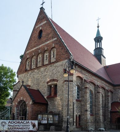 Zdjęcie nr 24: Kościół murowany, orientowany, jednonawowy, trójprzęsłowy, z transeptem i jednoprzęsłowym, węższym i niższym prezbiterium zamkniętym trójbocznie. Między nawą a transeptem po obu stronach znajdują się kruchty, do prezbiterium od strony północnej dostawiona kruchta złożona z dwóch lokalności. Ściany są rozczłonkowane filarami, tworzącymi płytkie arkadowe wnęki. Między nawą a prezbiterium arkada tęczowa. Sklepienie krzyżowe na gurtach spływających na filary. Prezbiterium oświetlają wąskie, prostokątne okna zamknięte ostrołukowo, w nawie i w transepcie znajdują się prostokątne okna prostokątne zamknięte półkoliście, w ścianie frontowej w dolnej części okna prostokątne zamknięte półkoliście, a w górnej podwójne okna prostokątne. Fasada ujęta dwiema narożnymi szkarpami, zwieńczona trójkątnie. Do niej dostawiona kruchta z dwuspadowym daszkiem i wejściem w kształcie prostokąta zamkniętego półkoliście. W kamiennej fasadzie znajdują się dołem okna prostokątne, zamknięte półkoliście, a górą  prostokątne, biforialne okna z nadprożem łukowatym wykonanym z cegły. Szczyt ceglany, podzielony na trzy strefy kamiennym wątkiem, z pięcioma wnękami prostokątnymi, zamkniętymi półkoliście, z wąskimi otworami w dolnej strefie i z owalnym oknem w drugiej. Elewacje boczne nawy ujęte skarpami. Dachy dwuspadowe, kryte dachówką, z wieżyczką na sygnaturkę.         