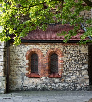 Zdjęcie nr 43: Kościół murowany, orientowany, jednonawowy, trójprzęsłowy, z transeptem i jednoprzęsłowym, węższym i niższym prezbiterium zamkniętym trójbocznie. Między nawą a transeptem po obu stronach znajdują się kruchty, do prezbiterium od strony północnej dostawiona kruchta złożona z dwóch lokalności. Ściany są rozczłonkowane filarami, tworzącymi płytkie arkadowe wnęki. Między nawą a prezbiterium arkada tęczowa. Sklepienie krzyżowe na gurtach spływających na filary. Prezbiterium oświetlają wąskie, prostokątne okna zamknięte ostrołukowo, w nawie i w transepcie znajdują się prostokątne okna prostokątne zamknięte półkoliście, w ścianie frontowej w dolnej części okna prostokątne zamknięte półkoliście, a w górnej podwójne okna prostokątne. Fasada ujęta dwiema narożnymi szkarpami, zwieńczona trójkątnie. Do niej dostawiona kruchta z dwuspadowym daszkiem i wejściem w kształcie prostokąta zamkniętego półkoliście. W kamiennej fasadzie znajdują się dołem okna prostokątne, zamknięte półkoliście, a górą  prostokątne, biforialne okna z nadprożem łukowatym wykonanym z cegły. Szczyt ceglany, podzielony na trzy strefy kamiennym wątkiem, z pięcioma wnękami prostokątnymi, zamkniętymi półkoliście, z wąskimi otworami w dolnej strefie i z owalnym oknem w drugiej. Elewacje boczne nawy ujęte skarpami. Dachy dwuspadowe, kryte dachówką, z wieżyczką na sygnaturkę.         