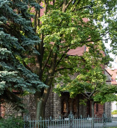 Zdjęcie nr 49: Kościół murowany, orientowany, jednonawowy, trójprzęsłowy, z transeptem i jednoprzęsłowym, węższym i niższym prezbiterium zamkniętym trójbocznie. Między nawą a transeptem po obu stronach znajdują się kruchty, do prezbiterium od strony północnej dostawiona kruchta złożona z dwóch lokalności. Ściany są rozczłonkowane filarami, tworzącymi płytkie arkadowe wnęki. Między nawą a prezbiterium arkada tęczowa. Sklepienie krzyżowe na gurtach spływających na filary. Prezbiterium oświetlają wąskie, prostokątne okna zamknięte ostrołukowo, w nawie i w transepcie znajdują się prostokątne okna prostokątne zamknięte półkoliście, w ścianie frontowej w dolnej części okna prostokątne zamknięte półkoliście, a w górnej podwójne okna prostokątne. Fasada ujęta dwiema narożnymi szkarpami, zwieńczona trójkątnie. Do niej dostawiona kruchta z dwuspadowym daszkiem i wejściem w kształcie prostokąta zamkniętego półkoliście. W kamiennej fasadzie znajdują się dołem okna prostokątne, zamknięte półkoliście, a górą  prostokątne, biforialne okna z nadprożem łukowatym wykonanym z cegły. Szczyt ceglany, podzielony na trzy strefy kamiennym wątkiem, z pięcioma wnękami prostokątnymi, zamkniętymi półkoliście, z wąskimi otworami w dolnej strefie i z owalnym oknem w drugiej. Elewacje boczne nawy ujęte skarpami. Dachy dwuspadowe, kryte dachówką, z wieżyczką na sygnaturkę.         