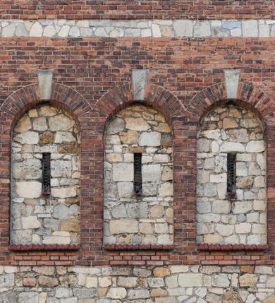 Zdjęcie nr 53: Kościół murowany, orientowany, jednonawowy, trójprzęsłowy, z transeptem i jednoprzęsłowym, węższym i niższym prezbiterium zamkniętym trójbocznie. Między nawą a transeptem po obu stronach znajdują się kruchty, do prezbiterium od strony północnej dostawiona kruchta złożona z dwóch lokalności. Ściany są rozczłonkowane filarami, tworzącymi płytkie arkadowe wnęki. Między nawą a prezbiterium arkada tęczowa. Sklepienie krzyżowe na gurtach spływających na filary. Prezbiterium oświetlają wąskie, prostokątne okna zamknięte ostrołukowo, w nawie i w transepcie znajdują się prostokątne okna prostokątne zamknięte półkoliście, w ścianie frontowej w dolnej części okna prostokątne zamknięte półkoliście, a w górnej podwójne okna prostokątne. Fasada ujęta dwiema narożnymi szkarpami, zwieńczona trójkątnie. Do niej dostawiona kruchta z dwuspadowym daszkiem i wejściem w kształcie prostokąta zamkniętego półkoliście. W kamiennej fasadzie znajdują się dołem okna prostokątne, zamknięte półkoliście, a górą  prostokątne, biforialne okna z nadprożem łukowatym wykonanym z cegły. Szczyt ceglany, podzielony na trzy strefy kamiennym wątkiem, z pięcioma wnękami prostokątnymi, zamkniętymi półkoliście, z wąskimi otworami w dolnej strefie i z owalnym oknem w drugiej. Elewacje boczne nawy ujęte skarpami. Dachy dwuspadowe, kryte dachówką, z wieżyczką na sygnaturkę.         