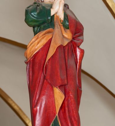 Zdjęcie nr 11: Grupa Ukrzyżowania złożona z ukrzyżowanego Chrystusa w typie christo vivo, stojących postaci Matki Boskiej i św. Jana oraz klęczącej Marii Magdaleny. Figura Chrystusa jest rzeźbą pełnoplastyczną, nieznacznie ściętą z tyłu, pozostałe są ścięte i wydrążone od tyłu. Zbawiciel przybity trzema gwoździami, z niemal prosto rozpostartymi rękami, z głową przechyloną na prawe ramię. Jego twarz jest pociągła, nos długi, oczy otwarte, twarz okolona kręconą, brązową brodą na głowie kręcone, sięgające szyi włosy i korona cierniowa pomalowana na zielono. Ręce z wyłamanymi barkami, z uwidocznionymi ścięgnami, klatka piersiowa wybrzuszona, z widocznymi żebrami i mostkiem, nogi smukłe z wyeksponowanymi kośćmi i mięśniami. Złocone perizonium przepasane podwójnym sznurem, z dwiema swobodnie rozwianymi połami po obu stronach bioder. Na naturalistycznie oddanym ciele zaznaczone strużki krwi. Na górnej belce titulus z literami: INRI&quot;. 
Matka Boska przedstawiona w pozycji stojącej, w kontrapoście, z rękami skrzyżowanymi na piersi. Głowę zwraca w kierunku Chrystusa, jej twarz jest owalna, włosy długie, brązowe, opadające na ramiona. Ubrana jest w czerwoną suknię z żółtą lamówką na rękawach, niebieski płaszcz o żółtym podbiciu i białą, długą chustę na głowie.    
Święty Jan ukazany w pozycji stojącej, w kontrapoście, z rękami złożonymi w geście modlitwy. Jego twarz jest owalna, oczy szeroko otwarte, włosy brązowe, kręcone, opadające na ramiona. Apostoł jest ubrany w zieloną tunikę i czerwony płaszcz z pomarańczowym podbiciem, przewieszony przez lewe ramię i ugiętą rękę. 
Po prawej stronie krzyża klęczy Maria Magdalena, ukazana prawym profilem, z prawą ręką, w której trzyma gąbkę wyciągniętą ku krzyżowi. Jej twarz jest pociągła z prostym nosem, włosy jasnobrązowe, długie, kręcone, opadające na plecy. Jest ubrana w zieloną tunikę i brązowy płaszcz o jaśniejszym podbiciu, opadający z lewego ramienia.
Na belce w kolorze czerwonym złocony napis: &quot;Benedictus XVI SPE SALVI FACTI SUMUS A(NNO) D(OMINI) MMVII&quot;.
